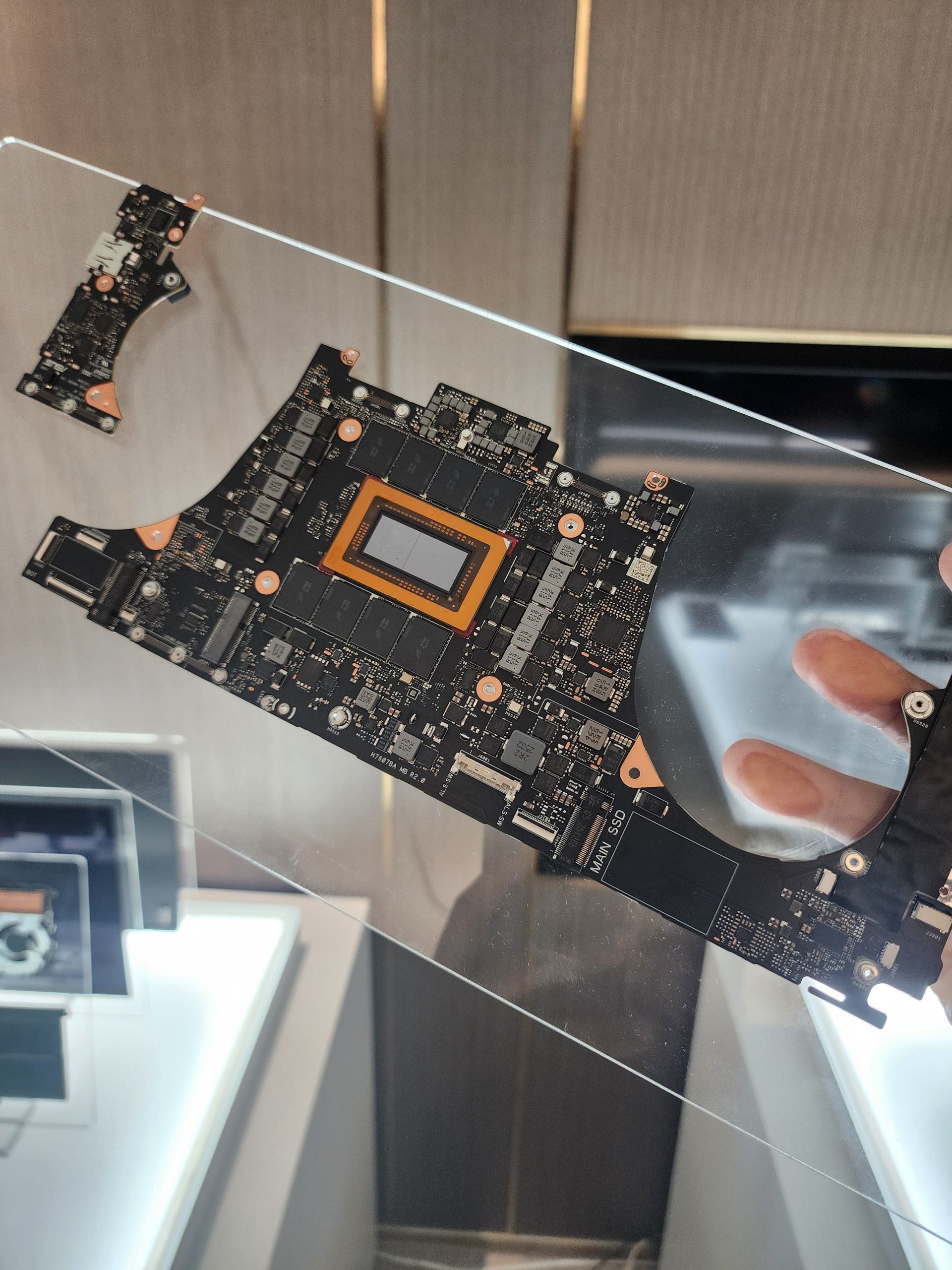 An AMD motherboard with visible components, including an 'M.2 SSD,' is displayed on a transparent stand.