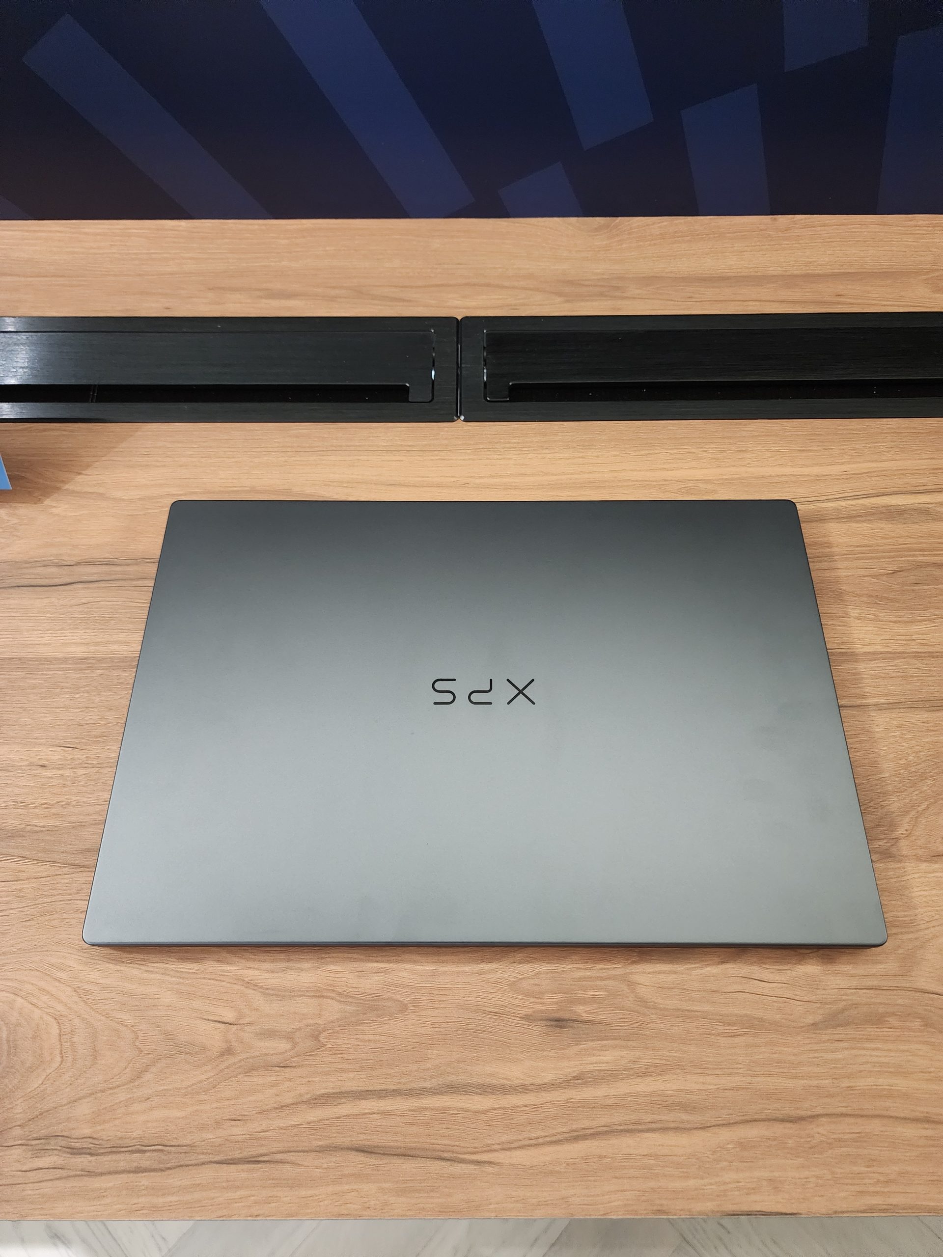 A Dell XPS laptop with a closed lid displayed on a wooden desk.