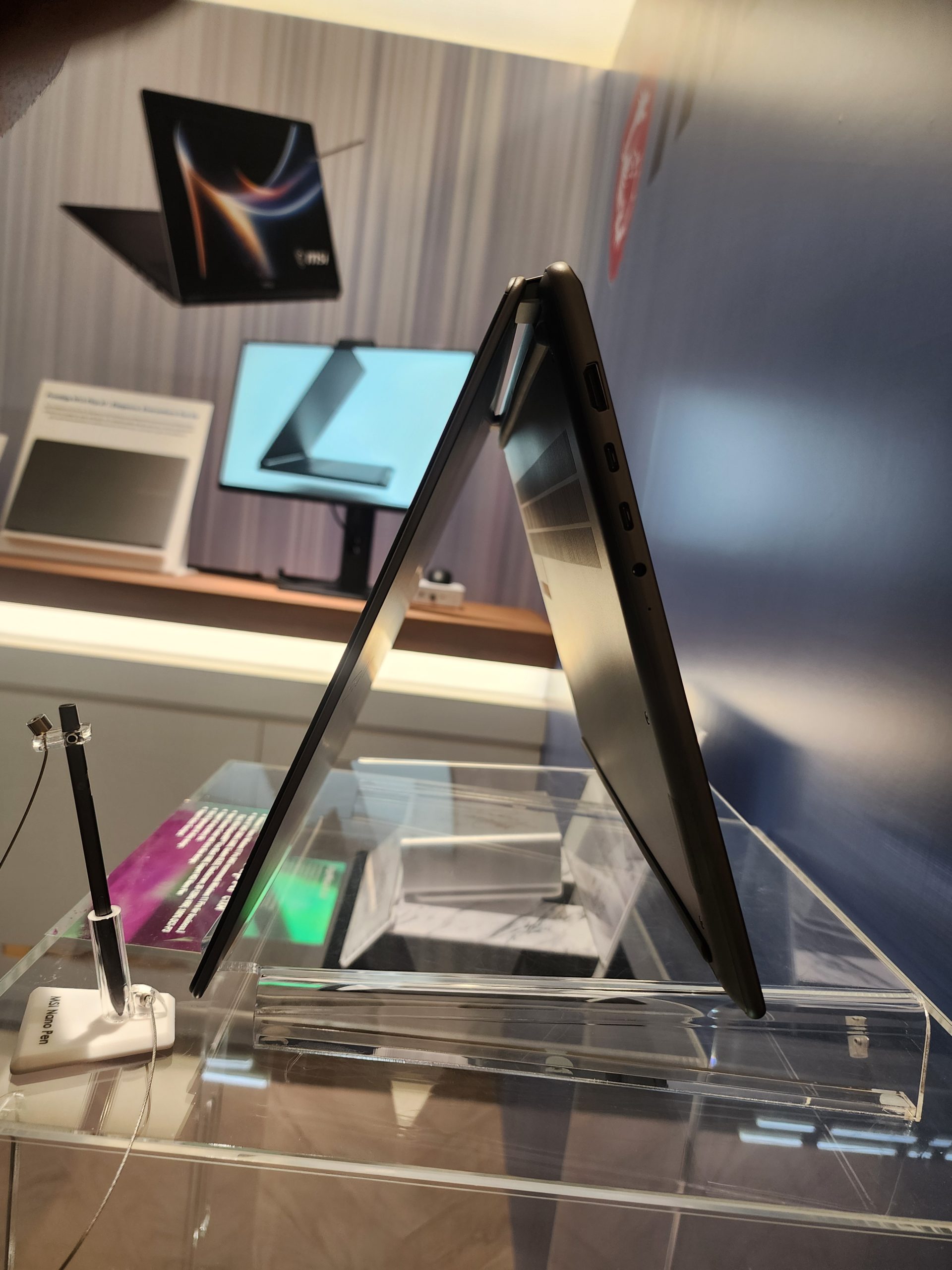 An MSI laptop displayed in a tent mode, with an MSI laptop and a monitor in the background.