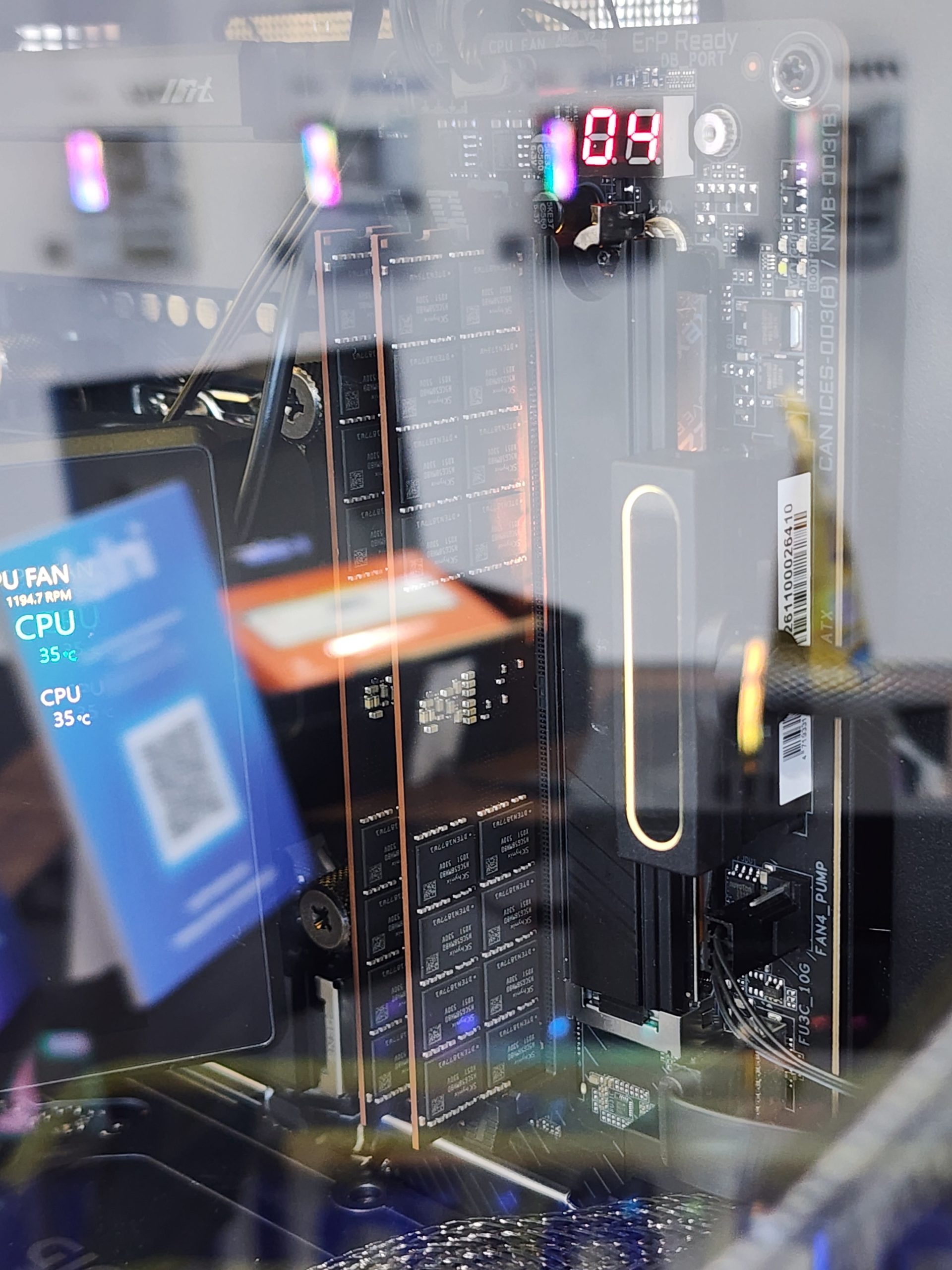 Close-up of a PC motherboard showing multiple storage drives and a digital display reading '84', with a nearby screen displaying 'CPU 35°C'.