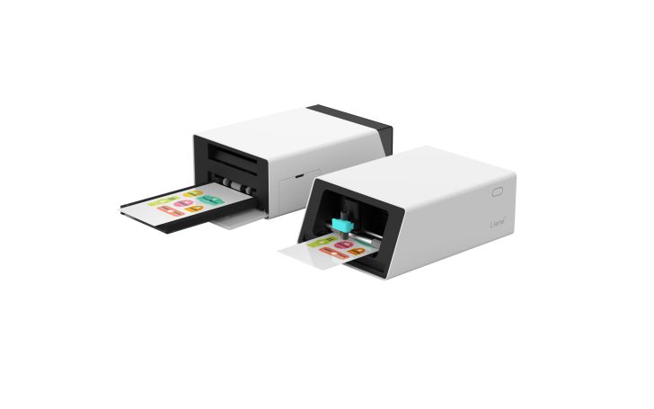 Two white Liene printers with colorful sticker sheets emerging from their trays.