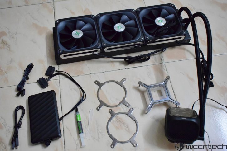 A DeepCool CPU liquid cooler kit with three fans, mounting brackets, cables, and thermal paste displayed on a tiled surface.
