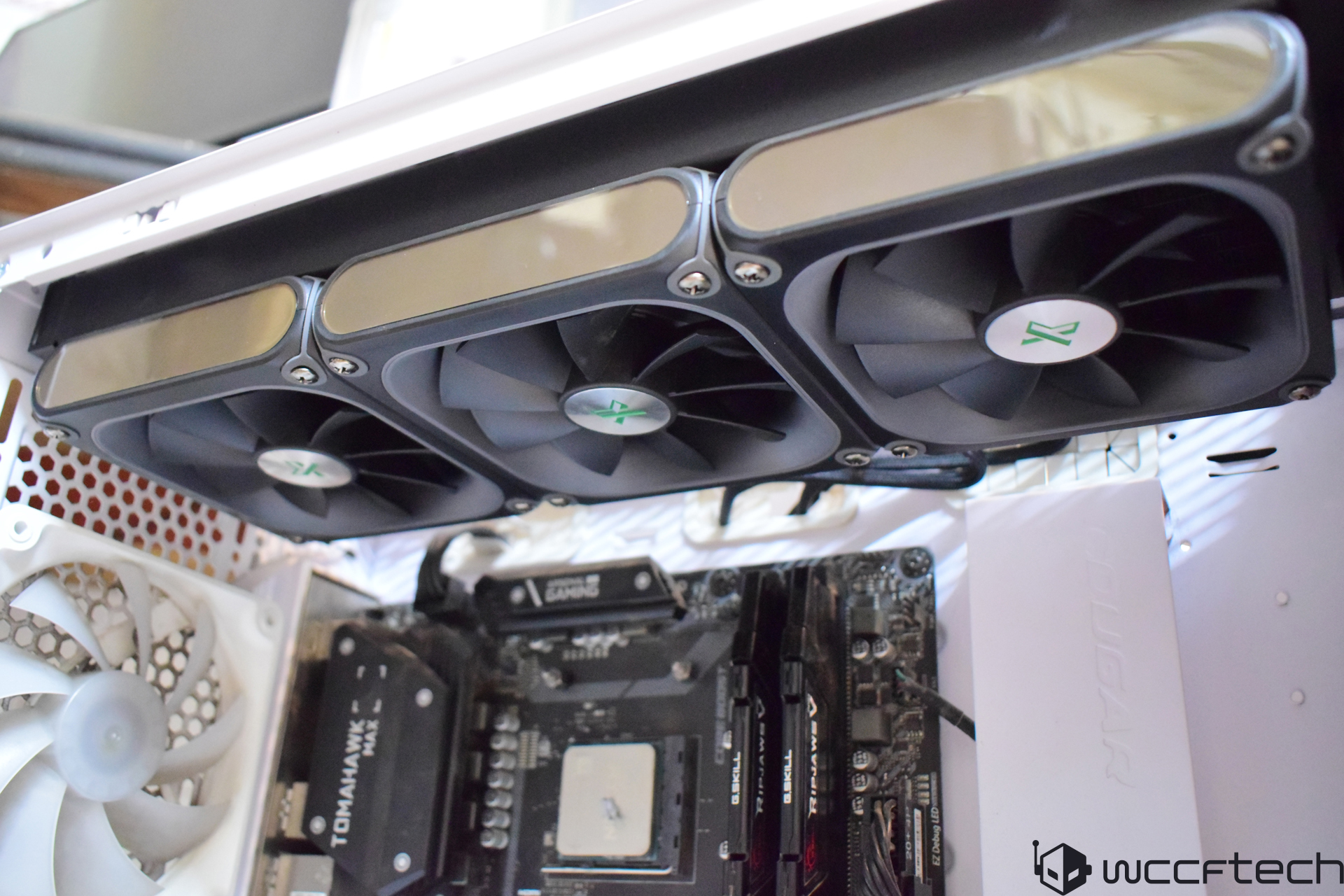 A computer build featuring an XPG radiator with three fans installed above a motherboard labeled 'TOMAHAWK MAX', alongside G.SKILL TridentZ RGB RAM and a COUGAR power supply.