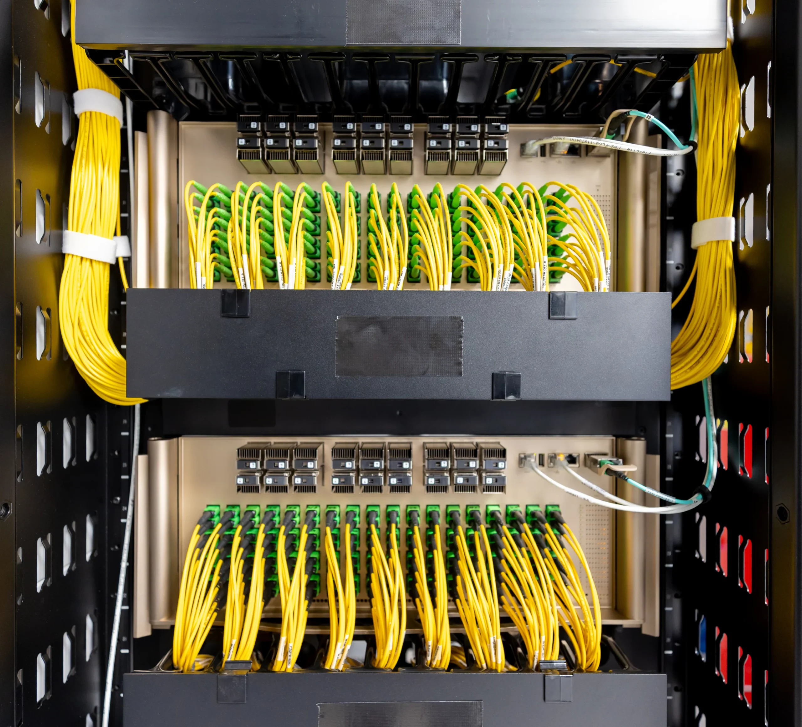 A server rack filled with neatly arranged yellow and green Ethernet cables connected to network switches.
