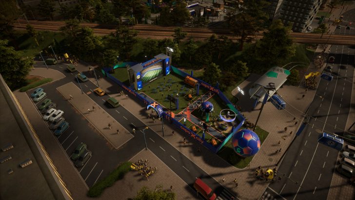 A top-down view of a Copa X City outdoor event area featuring a stage with a large screen and various soccer-themed interactive setups, surrounded by streets with parked cars and pedestrians.