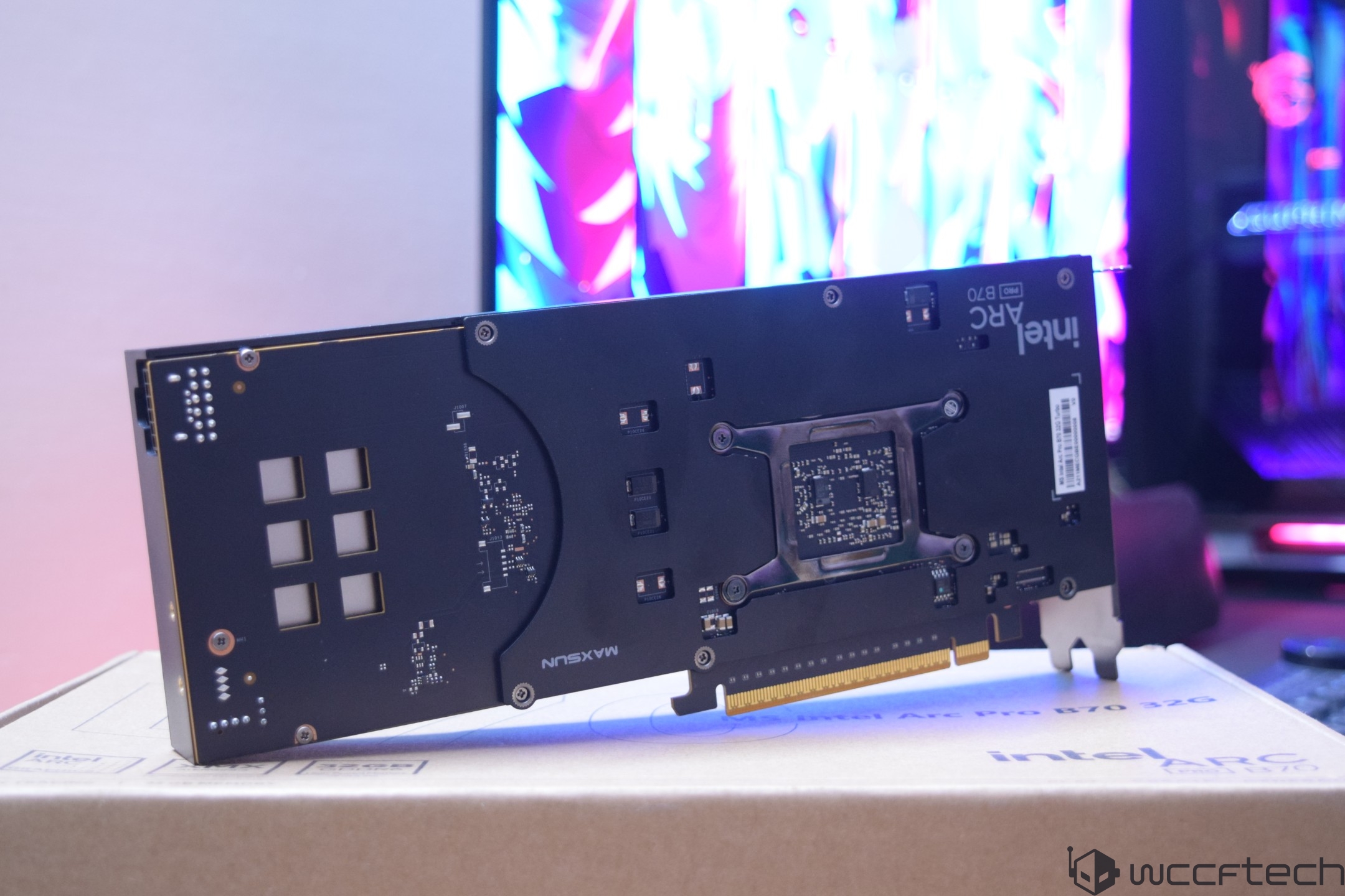 The image shows the back of an Intel Arc Pro B70 graphics card placed on a box labeled 'Intel Arc Pro B70 32GB' against a blurred background with vibrant colors.