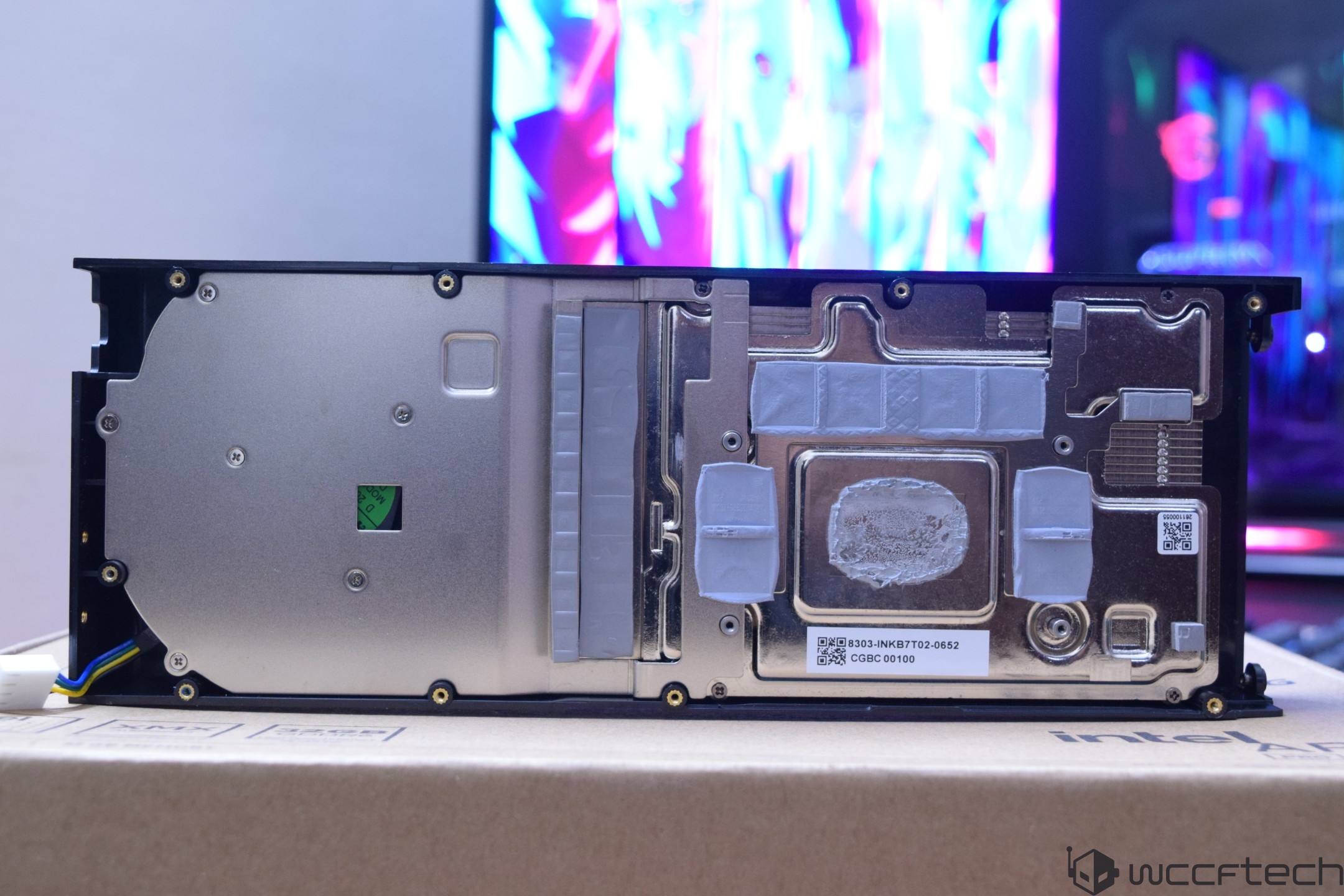 The internal view of an Intel graphics card with visible thermal paste and QR codes, placed on a cardboard box labeled 'Intel.'