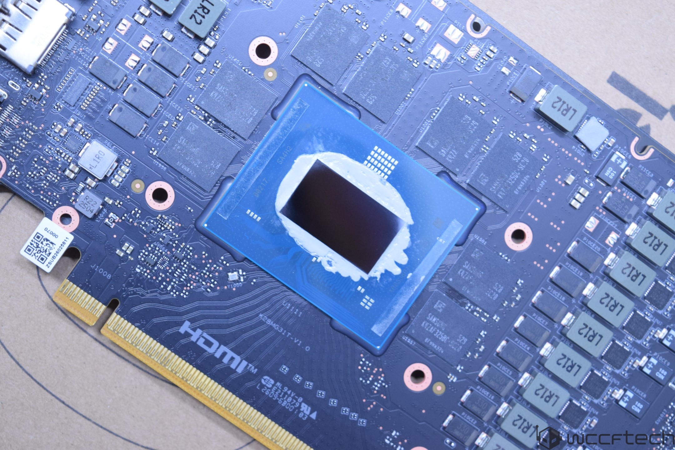 A printed circuit board with a visible Intel chip covered in thermal paste, surrounded by various capacitors and resistors, with an HDMI connection at the bottom edge.