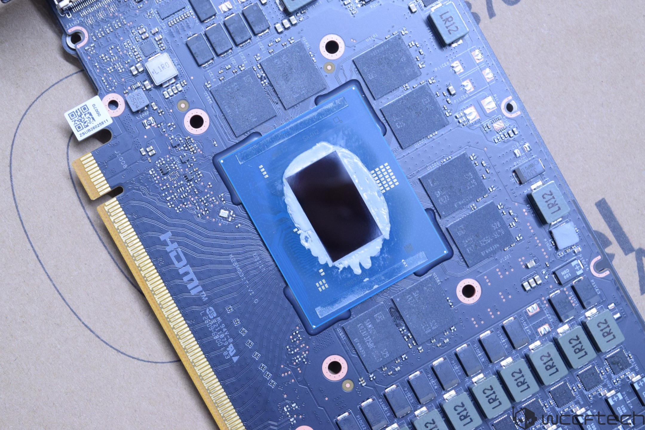 A close-up view of an Intel GPU with partially applied thermal paste and various chip components visible on the circuit board.