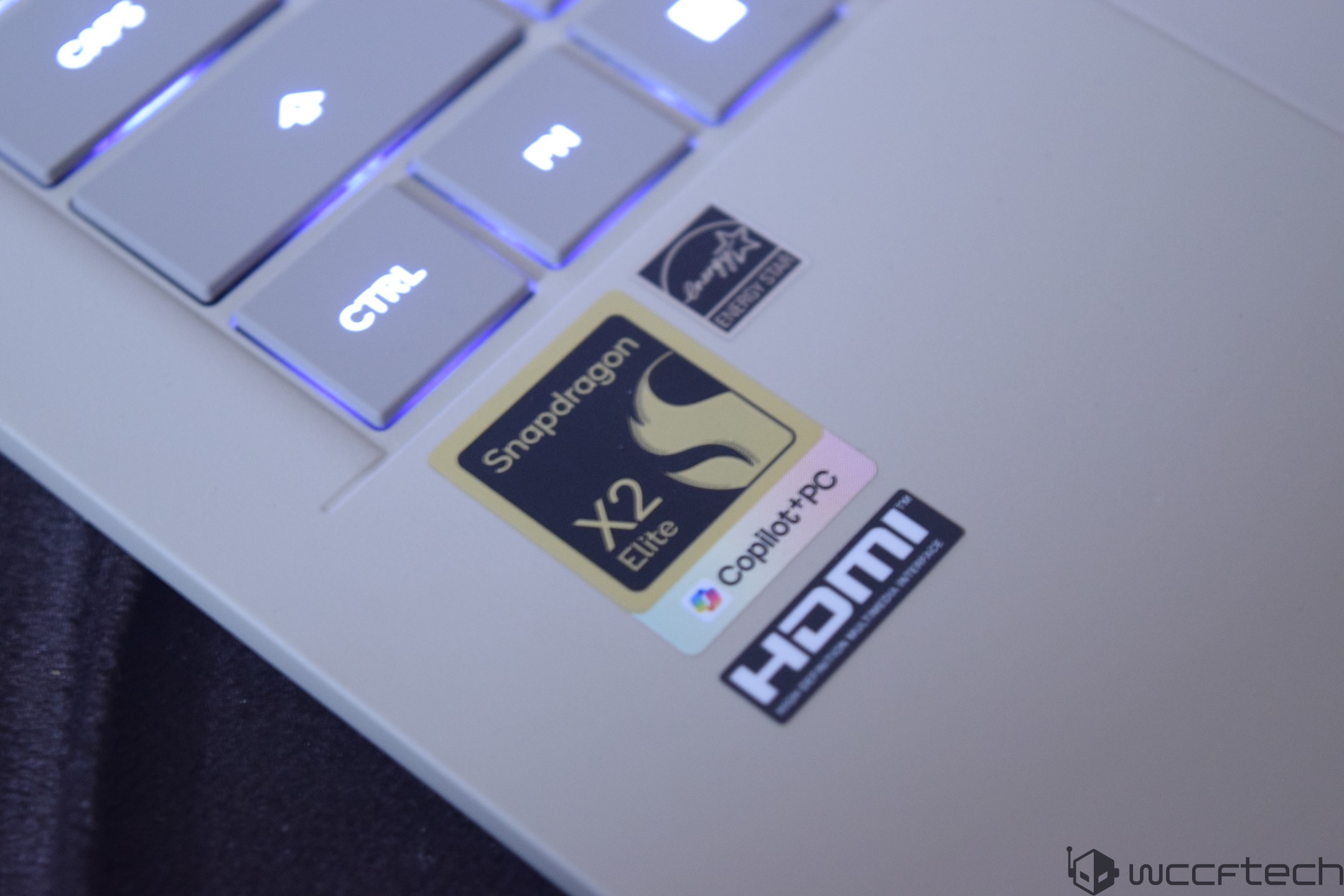 A white laptop features stickers for Snapdragon X2 Elite, Copilot+PC, and HDMI above a backlit 'CTRL' key.