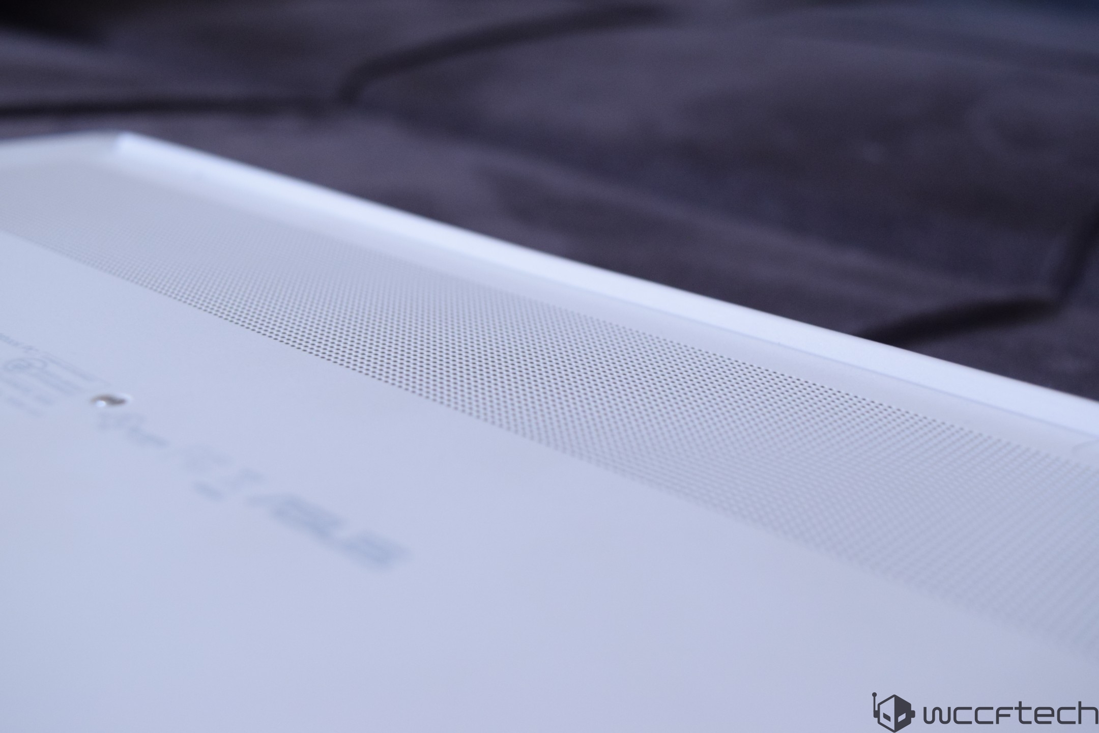 A close-up of the bottom part of an ASUS laptop with visible ventilation holes and a blurred 'ASUS' logo.
