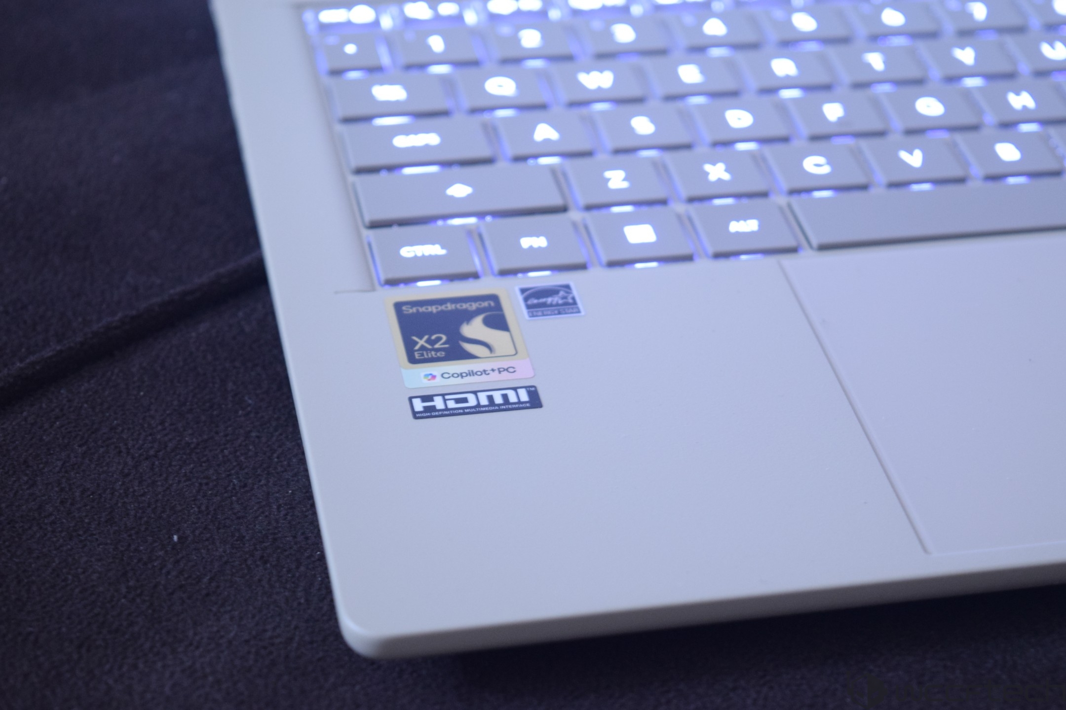 A close-up of a laptop keyboard with stickers showing 'Snapdragon X2 Elite,' 'Copilot + PC,' and 'HDMI' branding.