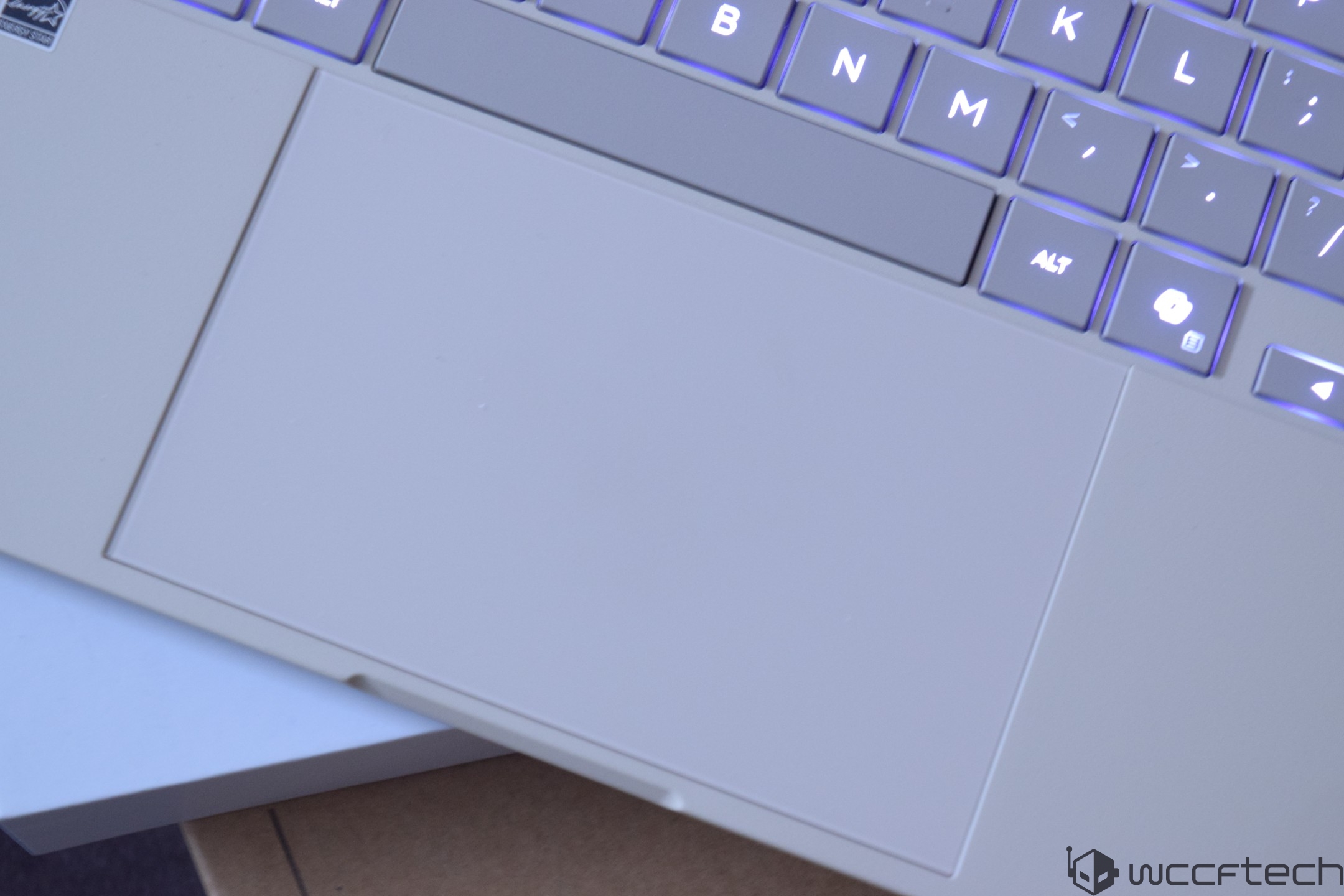A close-up of a laptop keyboard showing illuminated keys and a large trackpad.