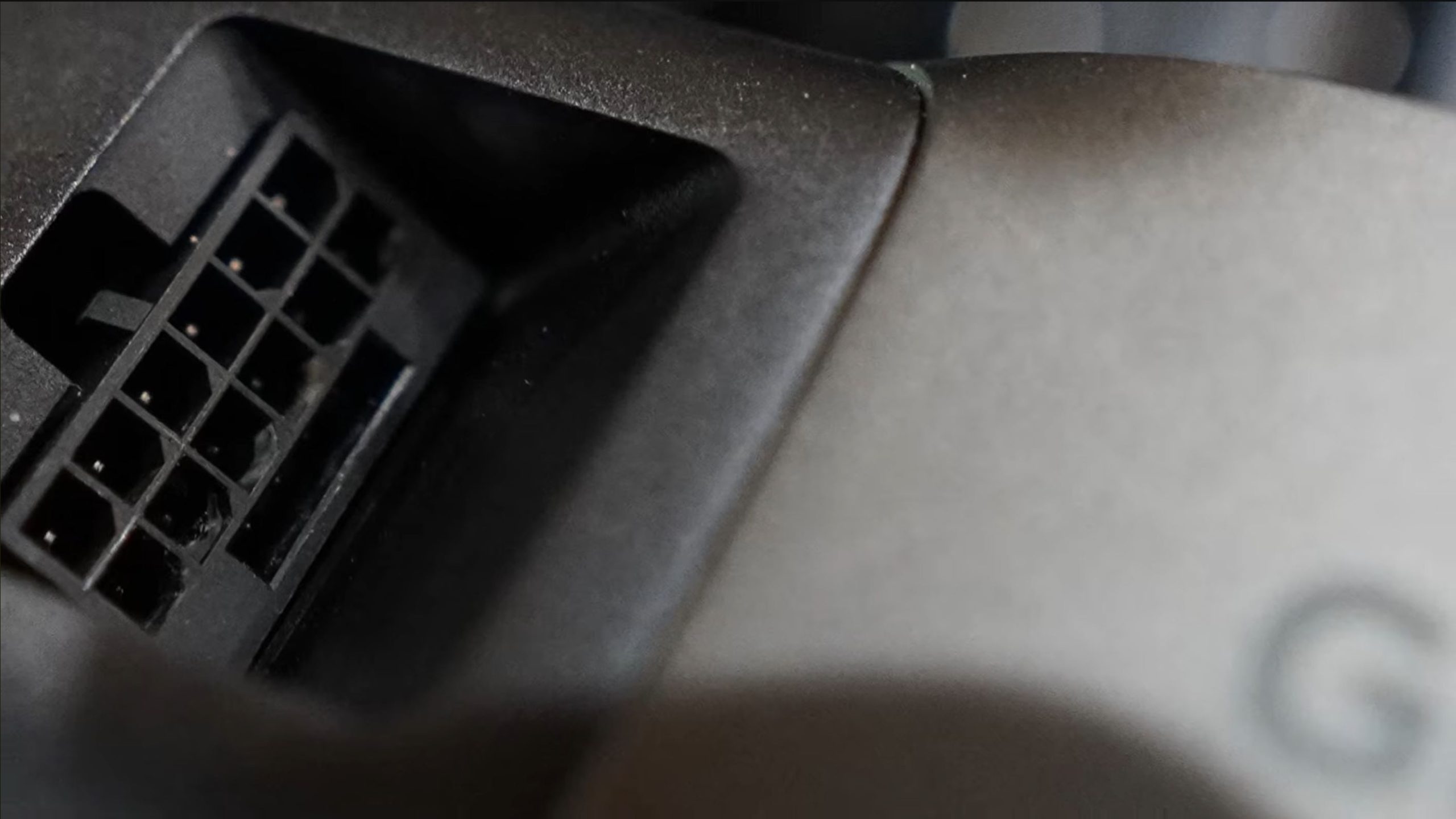 A close-up view of a 12VHPWR power connector on a graphics card with part of the Gigabyte logo visible.