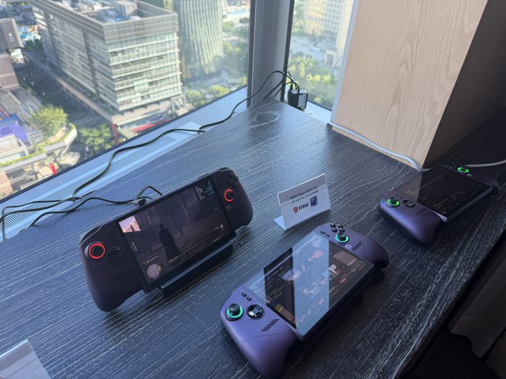 Three MSI Clutch 8EX Al handheld gaming devices displayed on a table, with one showing a character in a video game.