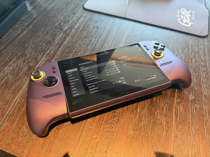 An MSI handheld gaming device is displayed on a wooden table showing an 'ACCESSIBILITY' settings menu on its screen.