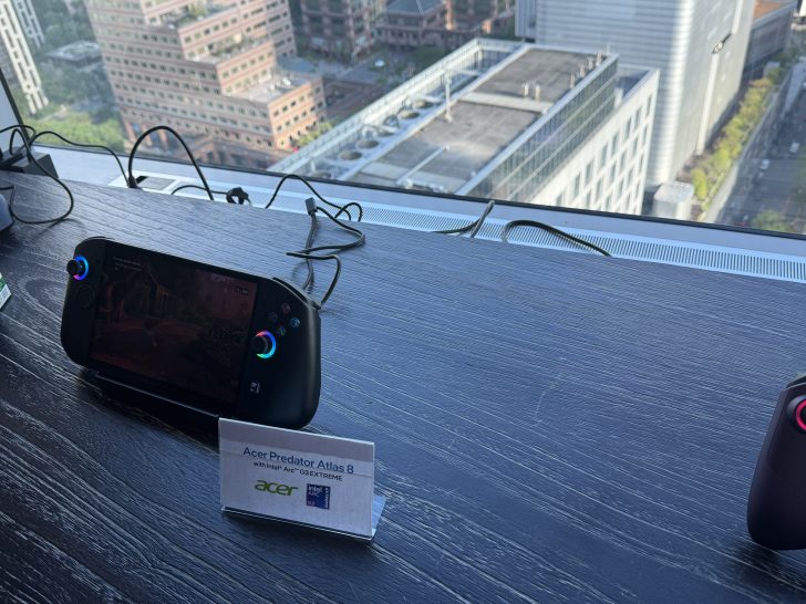 The Acer Predator Atlas 8 handheld console is displayed on a table, showing on-screen gameplay, with a sign reading 'Acer Predator Atlas 8 with Intel Arc G3 EXTREME.'