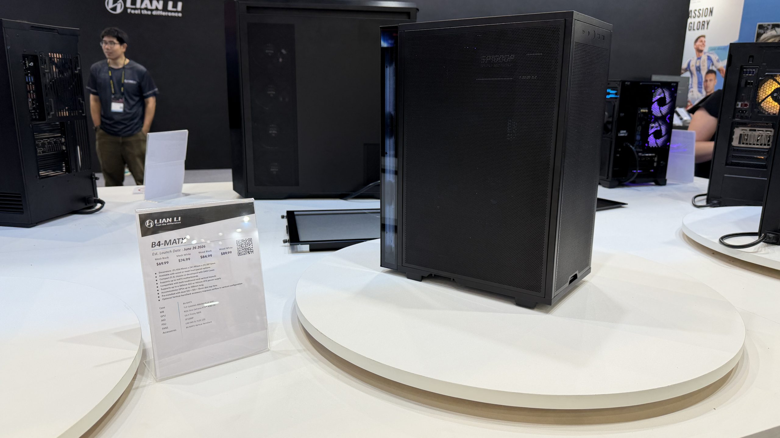 A Lian Li computer case model B4-MATX is displayed on a white platform with a sign detailing its estimated launch date as June 2024.