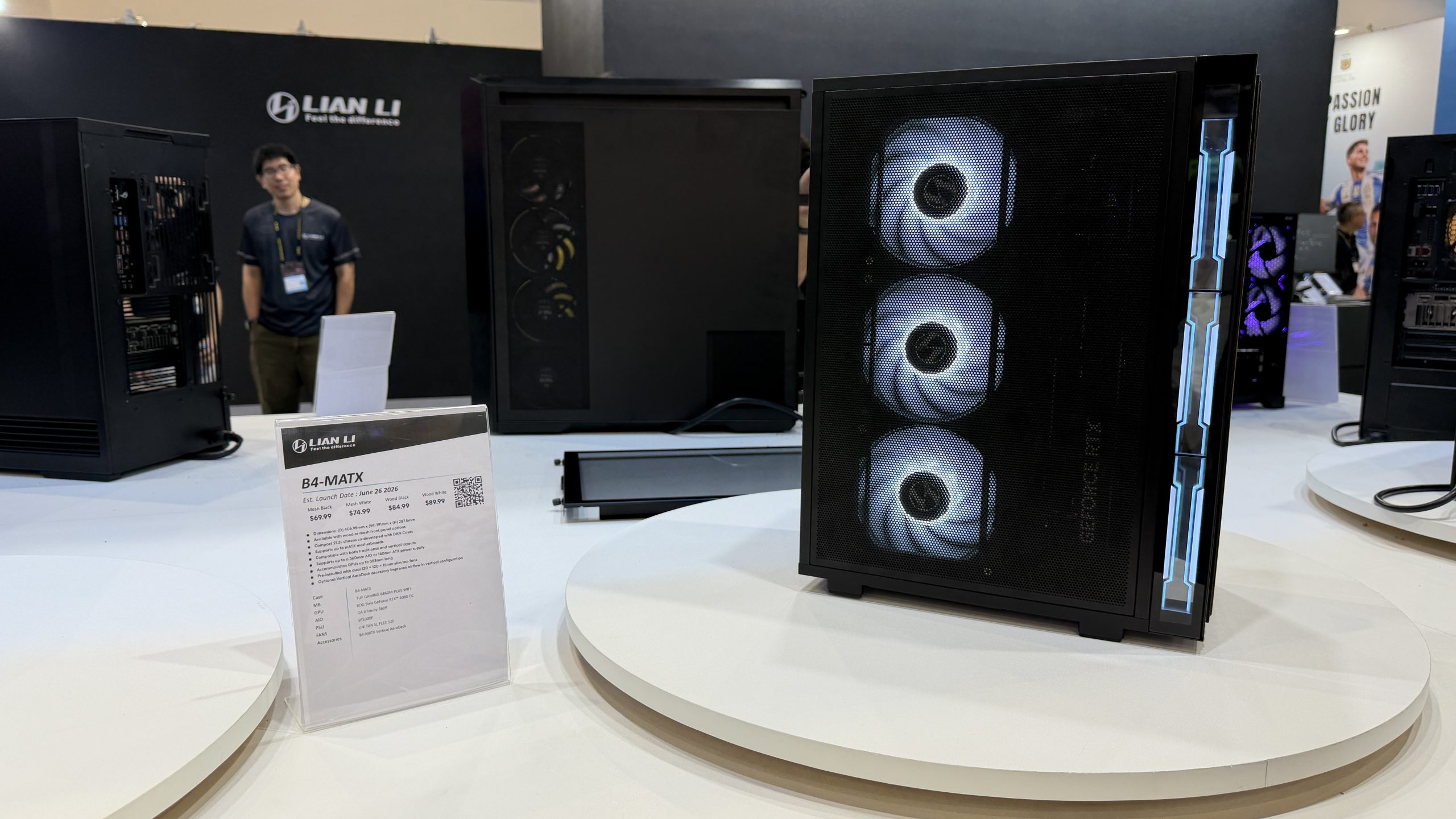 A Lian Li B4-MATX case is displayed with three illuminated fans visible at an event, accompanied by a product information card detailing launch date and pricing.