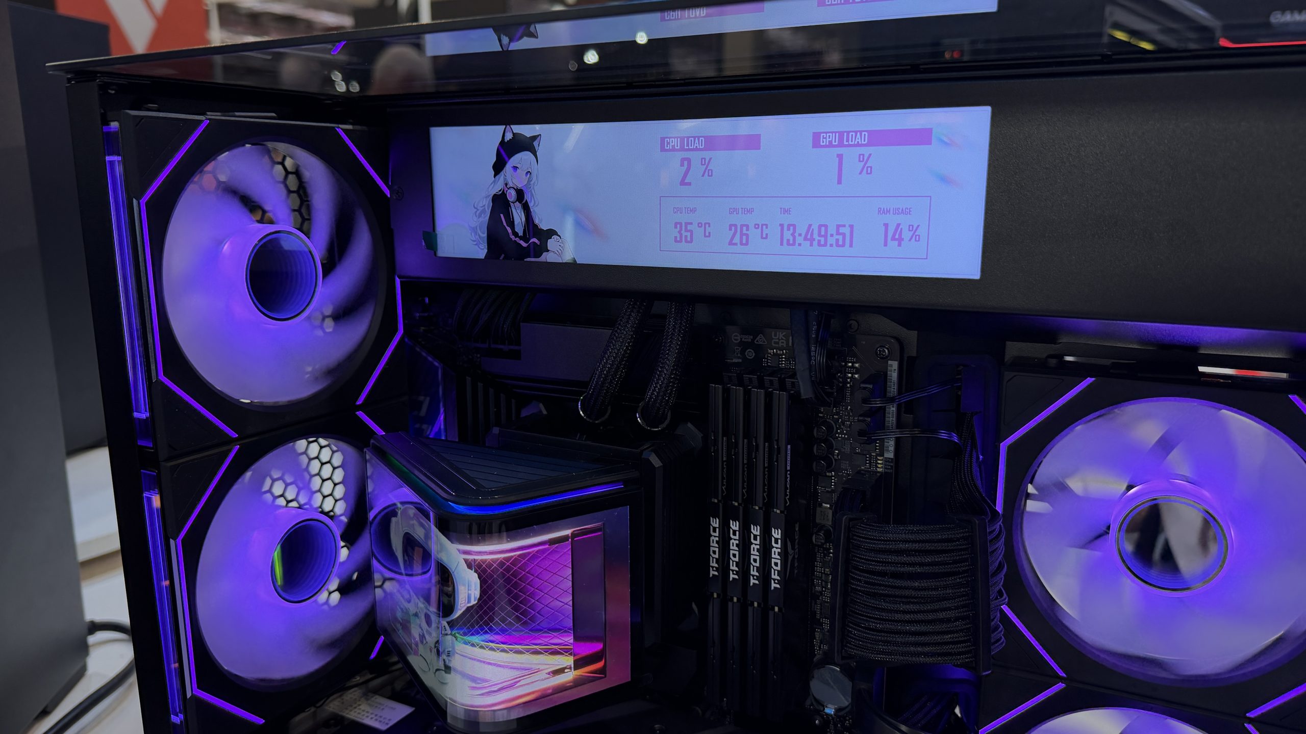 A custom PC setup with RGB lighting features a digital display showing CPU load at '2%', temperature '35°C', and RAM usage '14%', alongside T-Force branded RAM sticks.