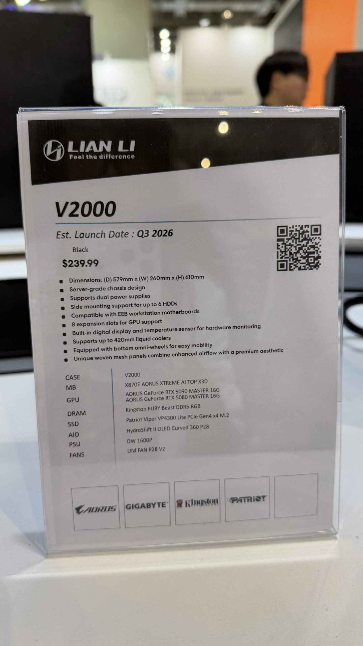 A promotional sign for the Lian Li V2000 case, showing an estimated launch date of Q3 2026 and a price of $239.99, with specifications and compatible hardware listed, including AORUS GeForce RTX 5090 MASTER 16G and other components.