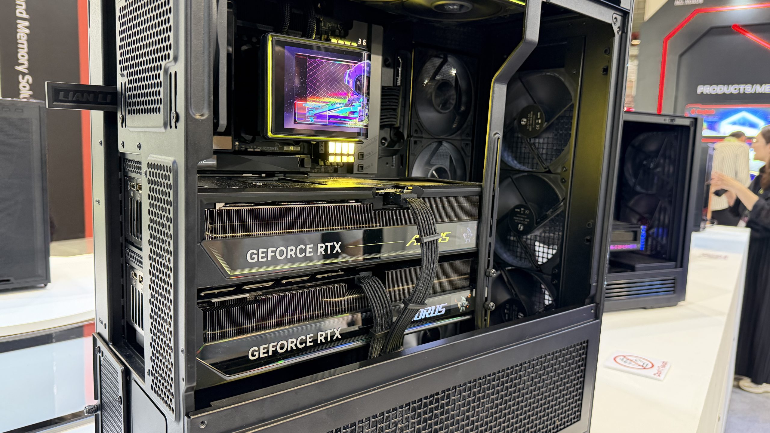 A PC case by Lian Li houses two ASUS GeForce RTX graphics cards, with visible cable management and internal cooling fans.