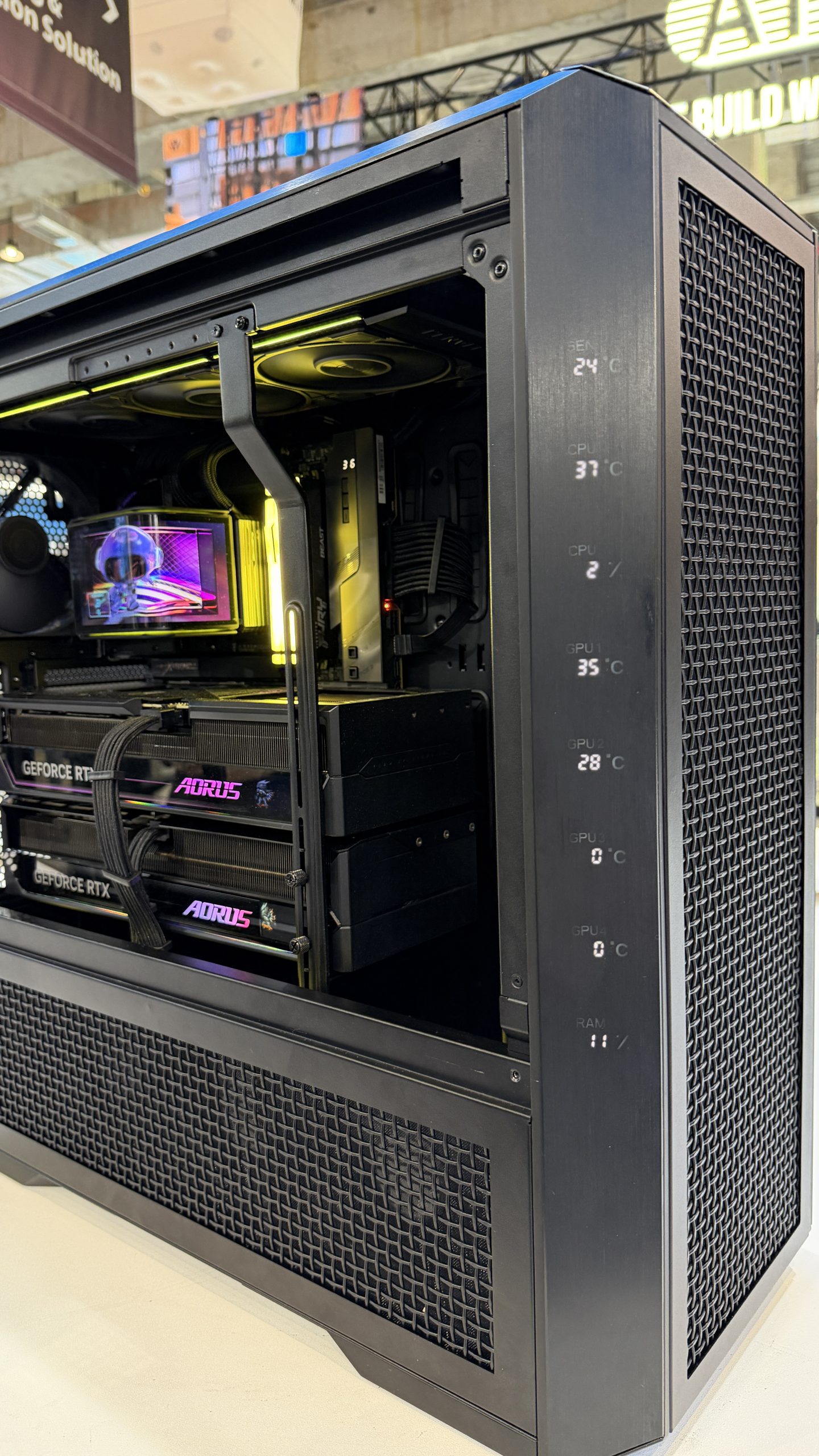 A computer tower with visible components including dual NVIDIA GeForce RTX graphics cards, an AORUS graphics card, and temperature readings on the side panel showing CPU and GPU temperatures.