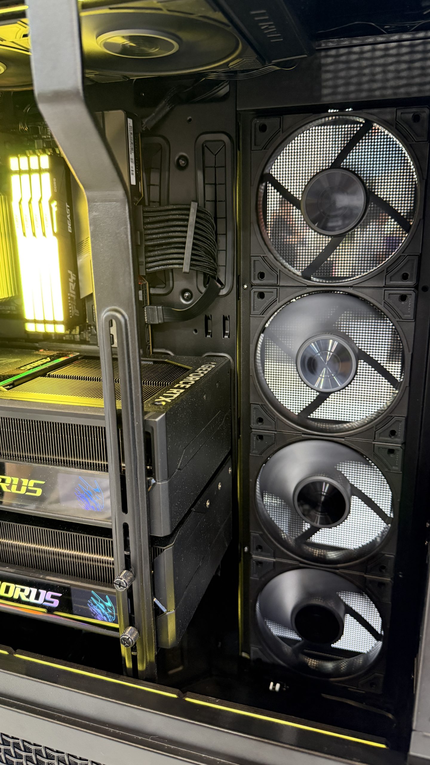 The interior of a computer case featuring a Gigabyte AORUS GeForce RTX 4090 graphics card, illuminated RAM modules labeled 'AORUS,' and three large cooling fans.