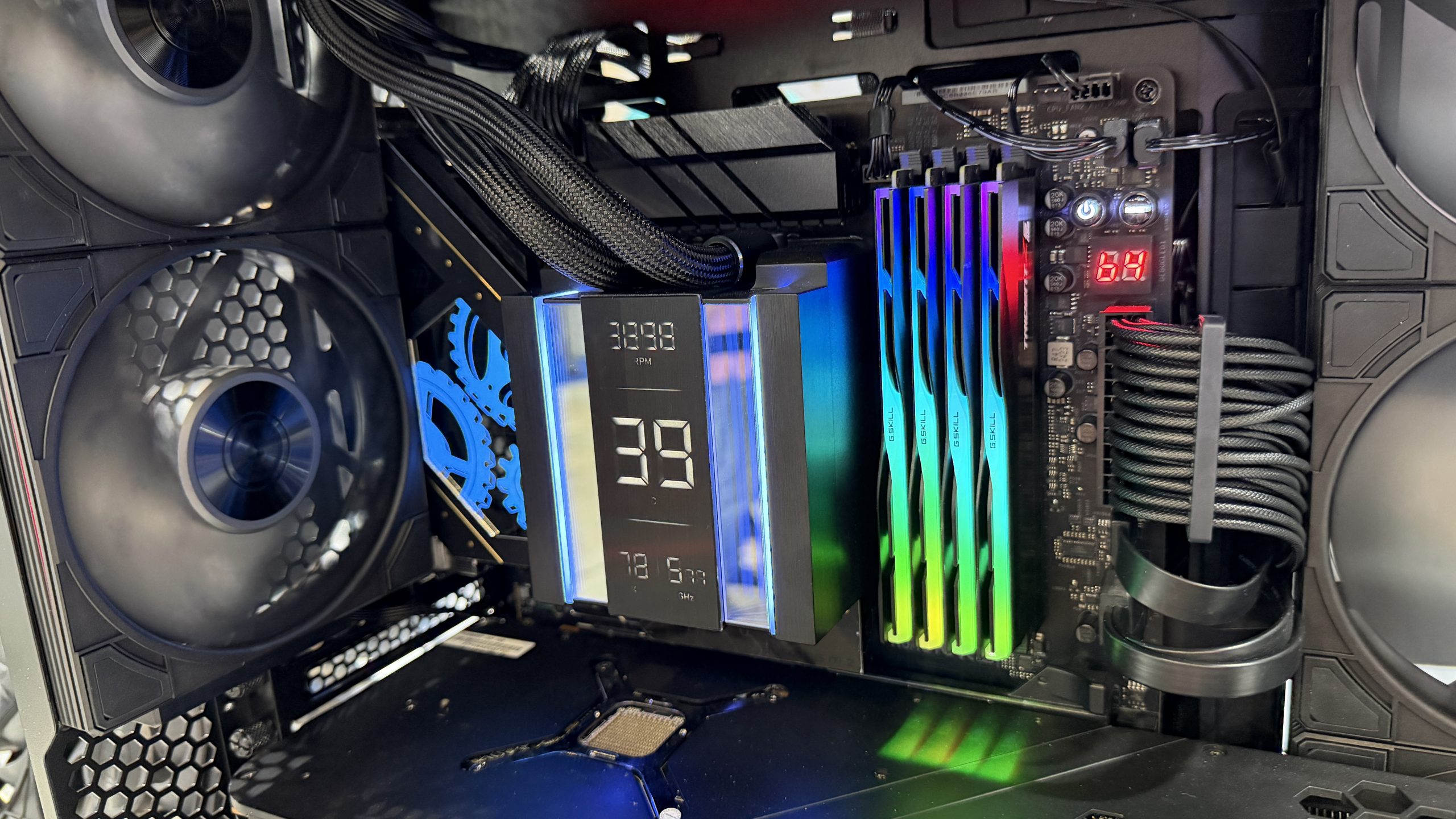 A custom PC build featuring a cooling system displaying '3988 RPM,' G.Skill RGB RAM modules, and two black cooling fans inside the case.
