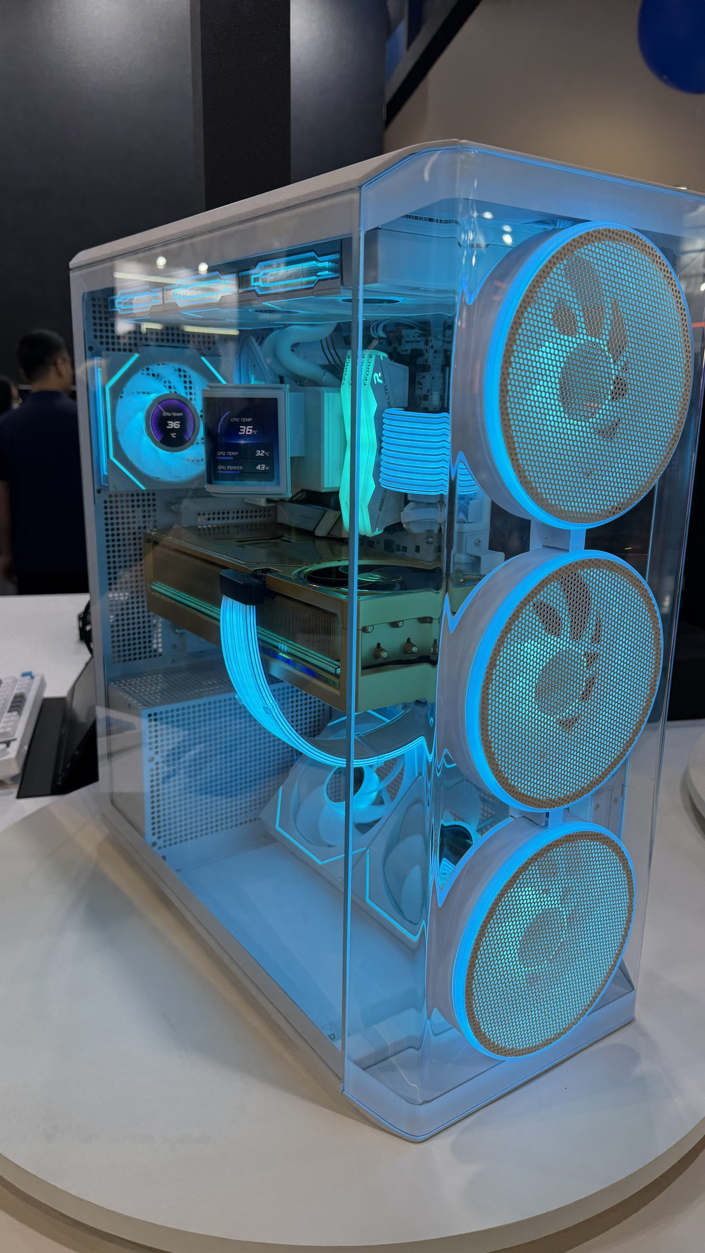 A custom PC case with blue LED lighting features three front fans, a visible GPU, braided cables, and a digital display showing 'CPU Temp 36°c' and 'GPU Temp 32°c'.