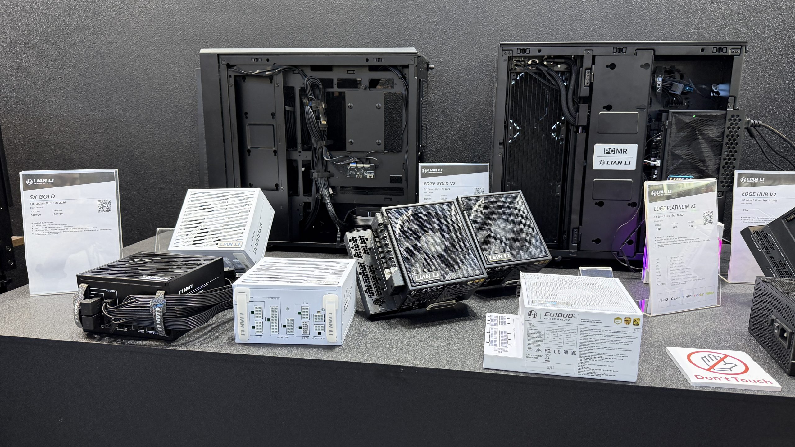 A display of Lian Li computer components, including SX Gold and Edge Platinum V2 power supplies, with accompanying specifications and a sign reading 'Don't Touch.'