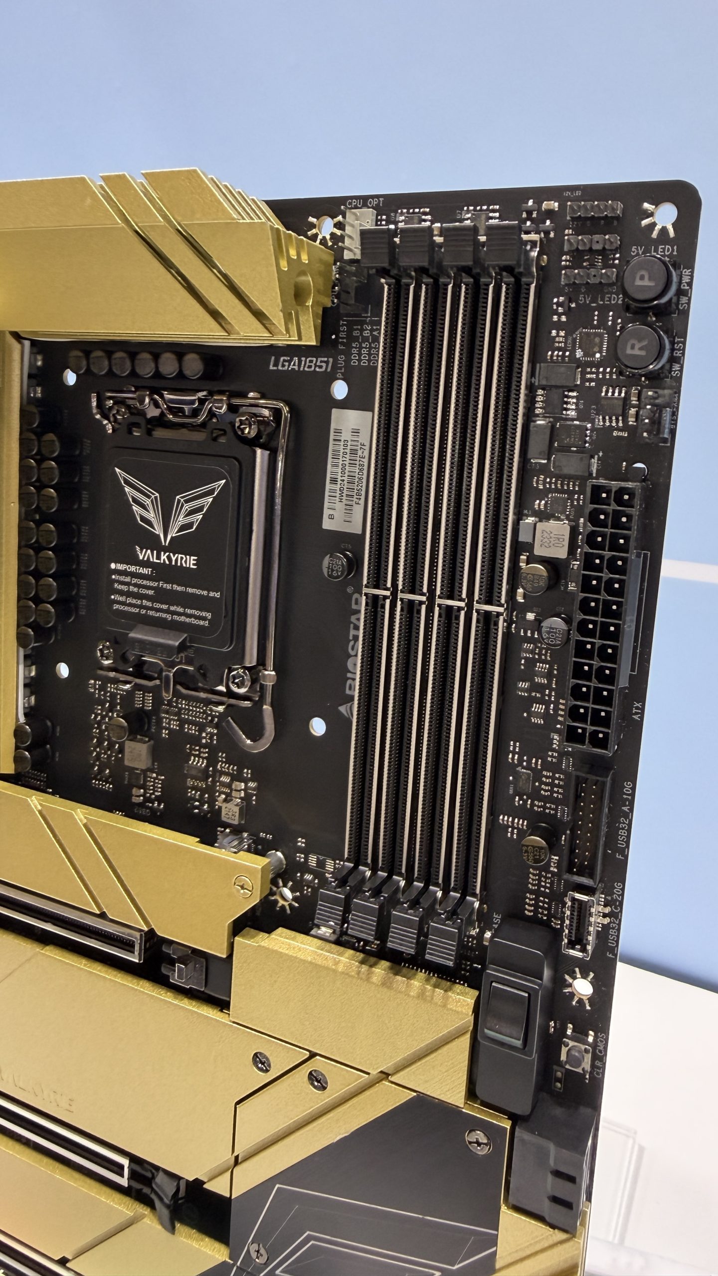 A Biostar Valkyrie motherboard with a gold heatsink, featuring 'LGA1851' socket and multiple DDR5 RAM slots.