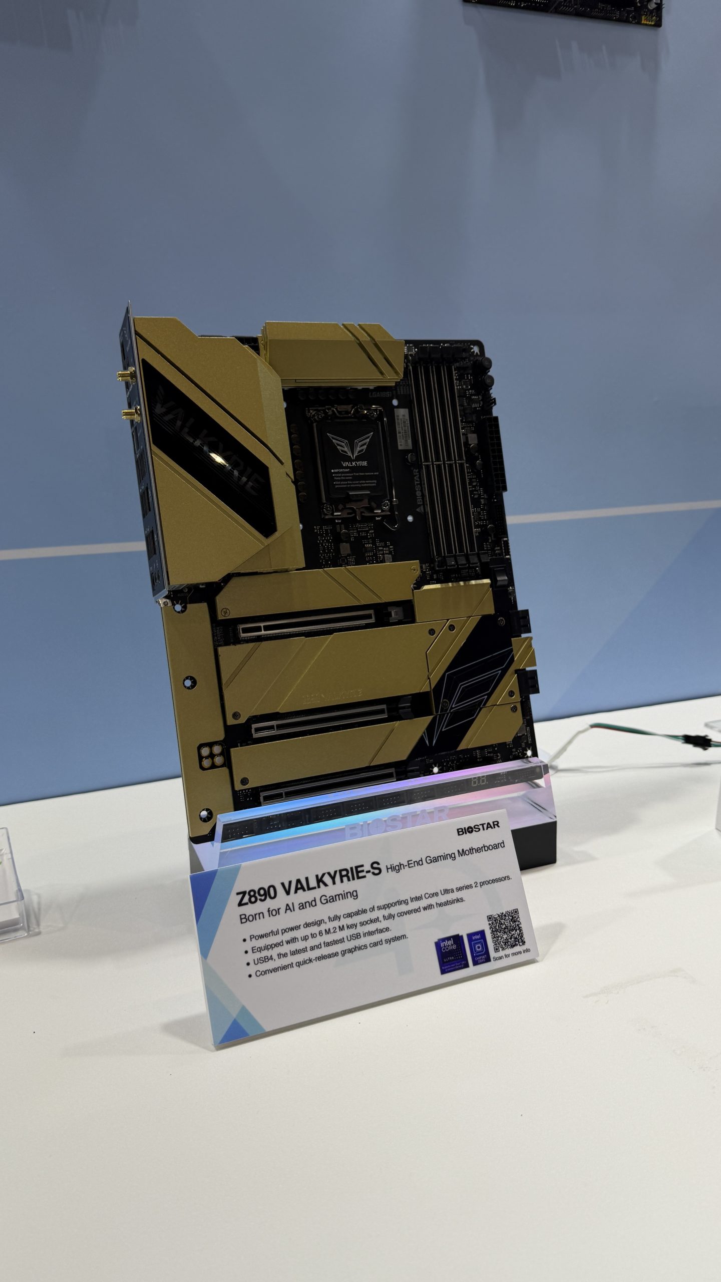 A Biostar Z890 Valkyrie-S high-end gaming motherboard is displayed, featuring gold accents and connections for multiple components, with a sign highlighting features such as Intel Core Ultra series 2 compatibility and USB4 support.