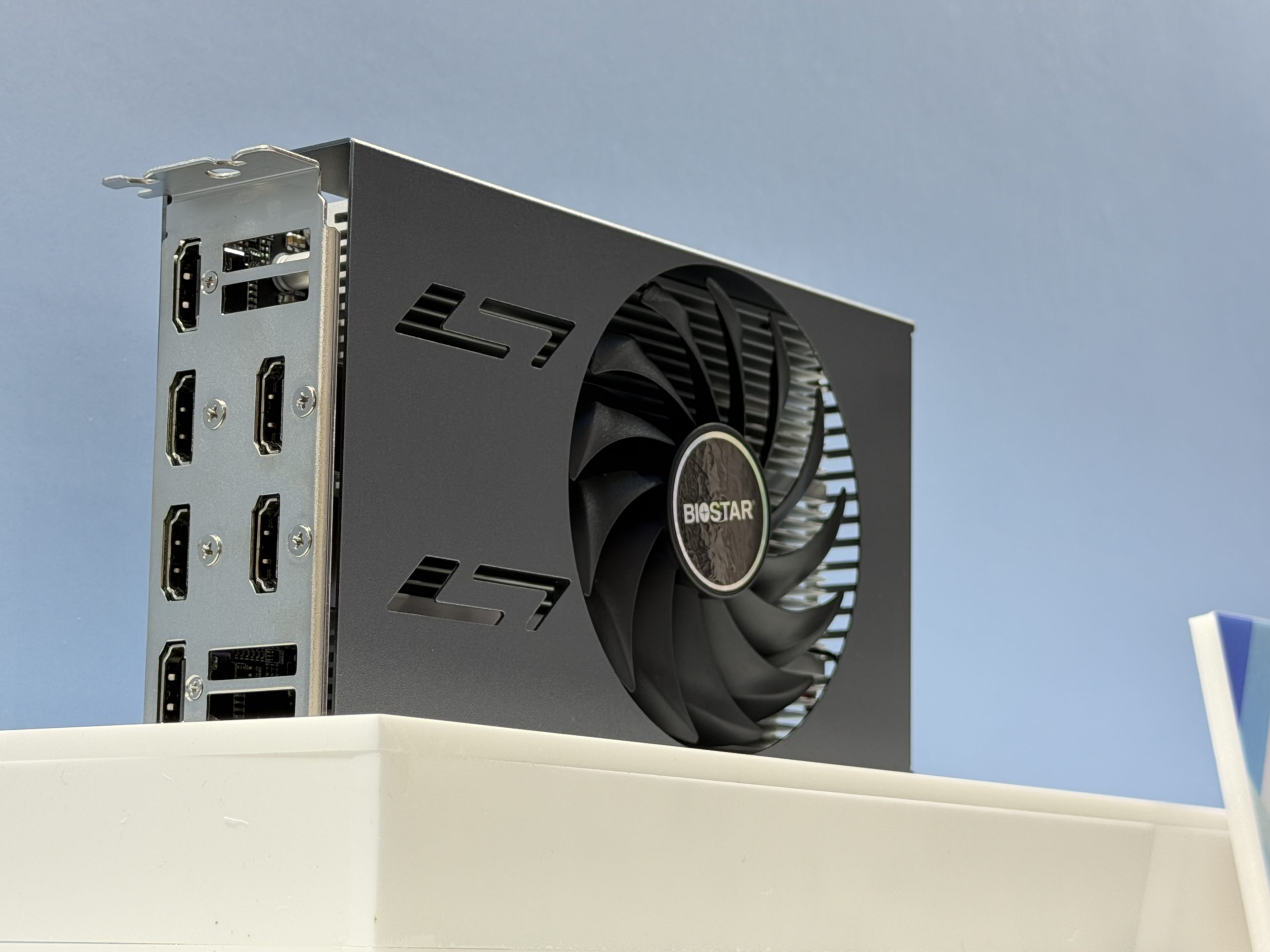 A Biostar graphics card with multiple HDMI and DisplayPort outputs is displayed on a white surface.