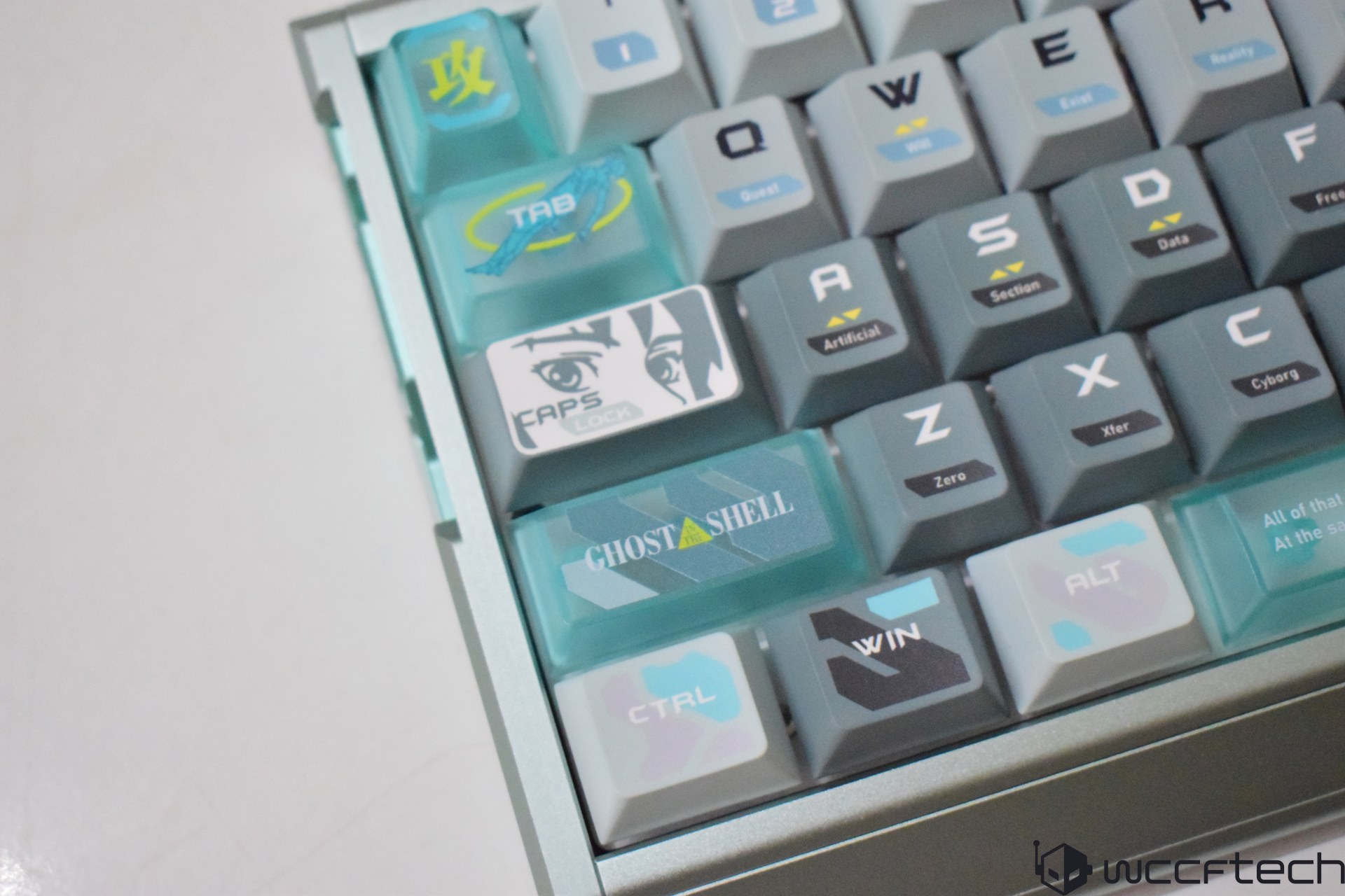A mechanical keyboard features custom keycaps with text such as 'GHOST IN THE SHELL,' 'CAPS LOCK,' and 'Artificial' prominently visible.