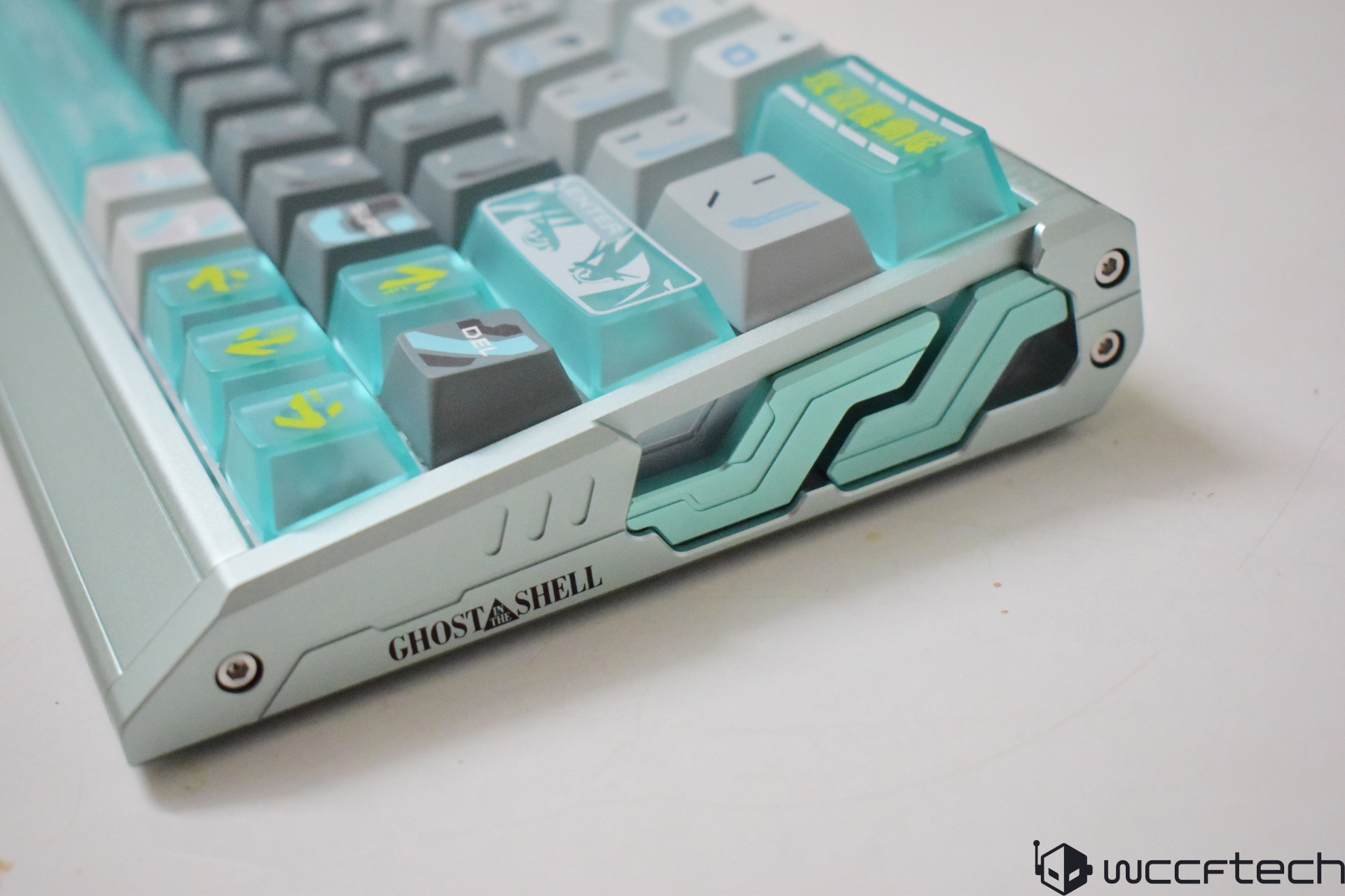 A mechanical keyboard features custom keycaps with a Ghost in the Shell design and vibrant teal accents.
