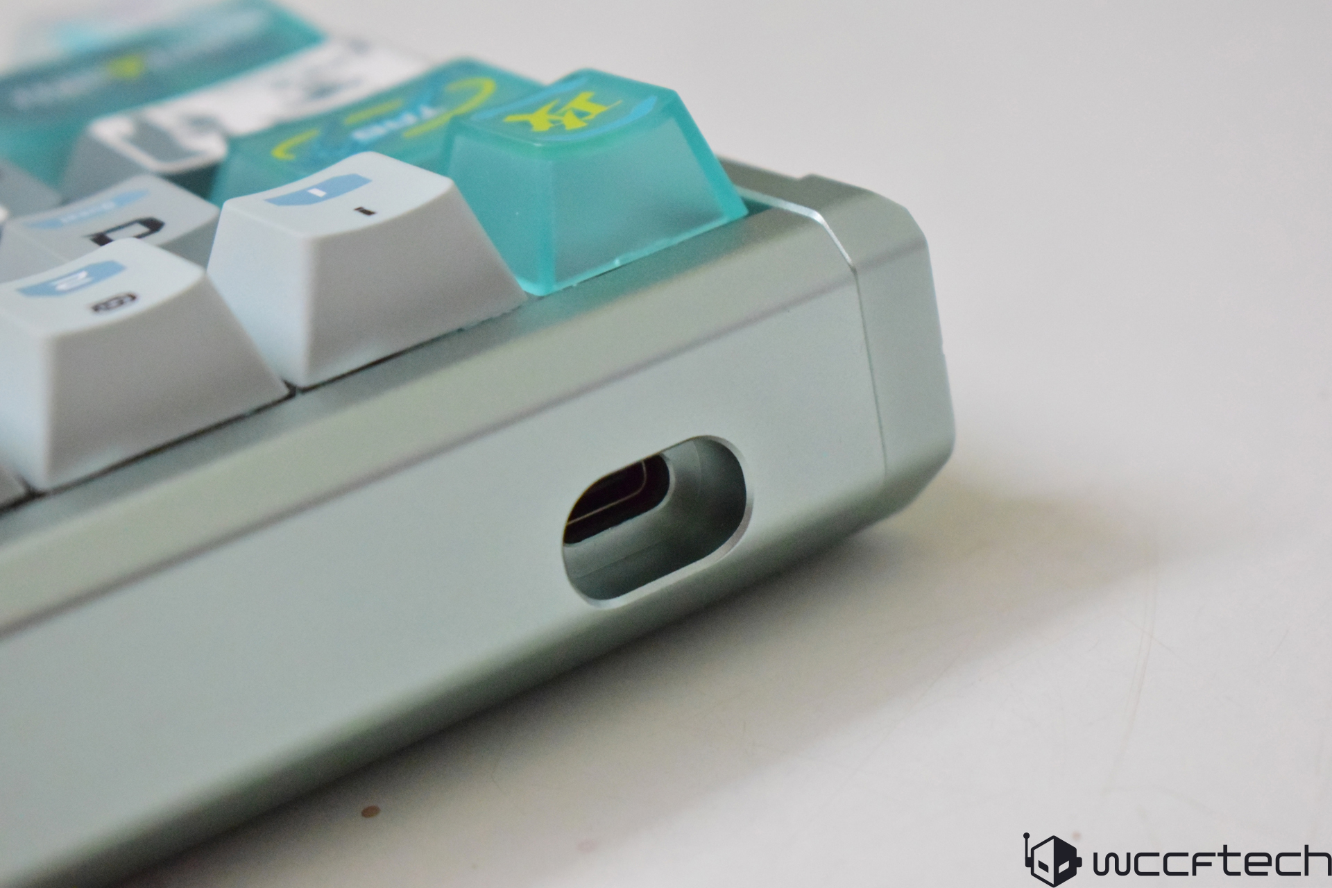 Close-up of an unbranded mechanical keyboard featuring a USB-C port and light-blue-tinted keycaps.