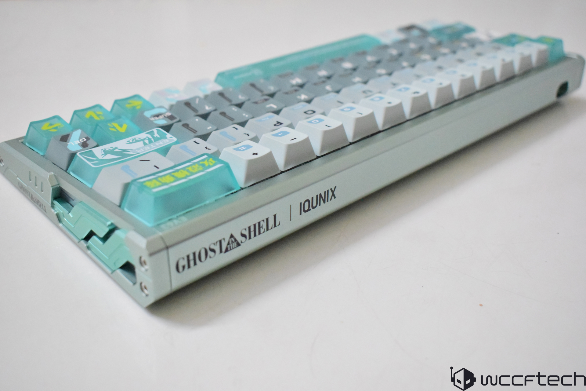 A close-up of the IQUNIX Ghost in the Shell themed mechanical keyboard featuring green and gray keycaps with unique designs.