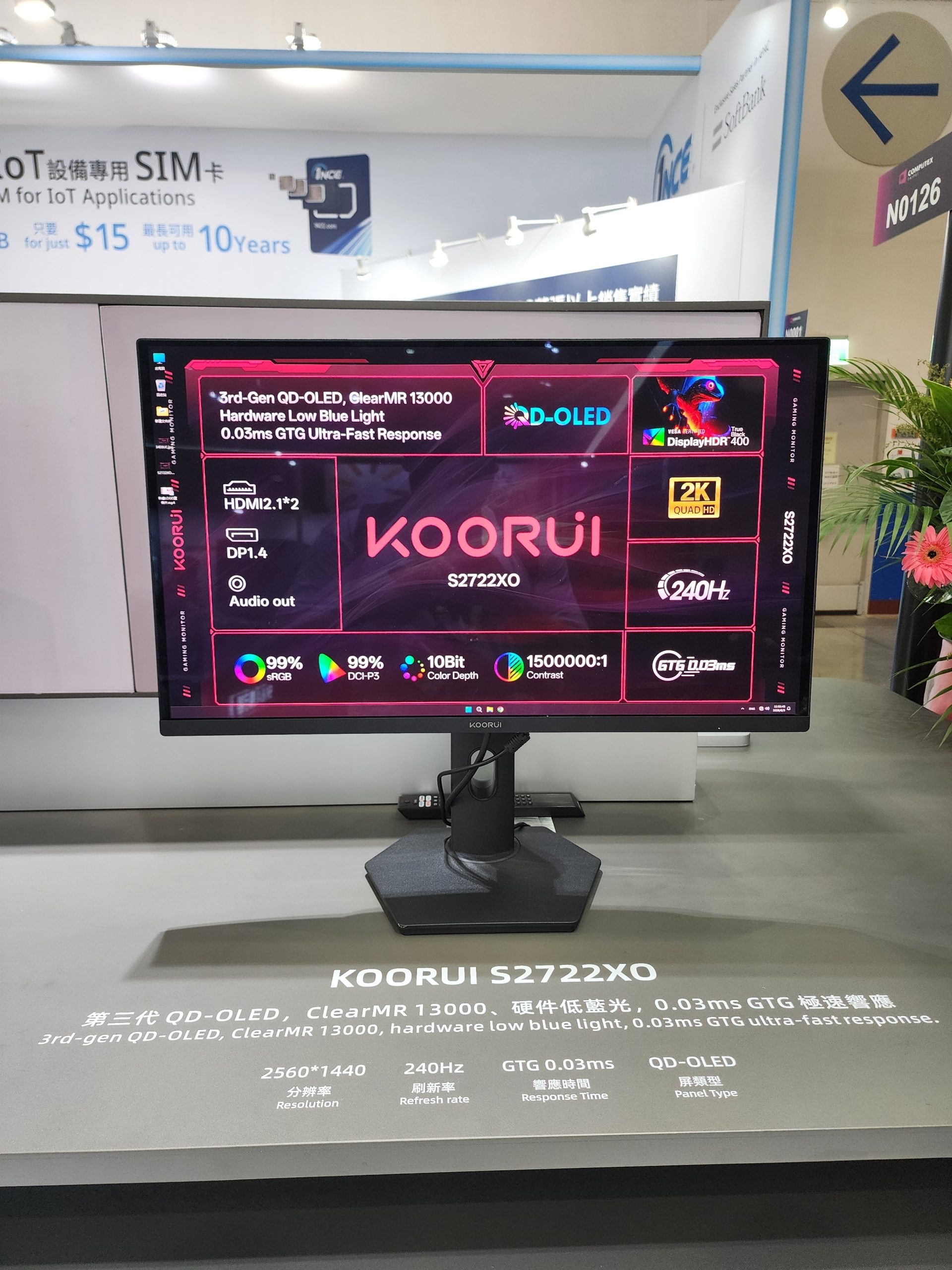 A Koorui S2722XO monitor showcases specifications including '3rd-Gen QD-OLED,' '240Hz,' '0.03ms GTG Ultra-Fast Response,' and 'DisplayHDR 400' with a 2560x1440 resolution while placed on a display stand.