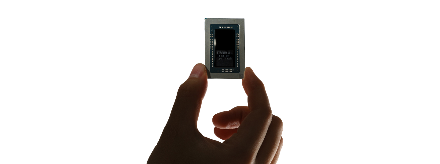A hand holding an NVIDIA chip against a white background.