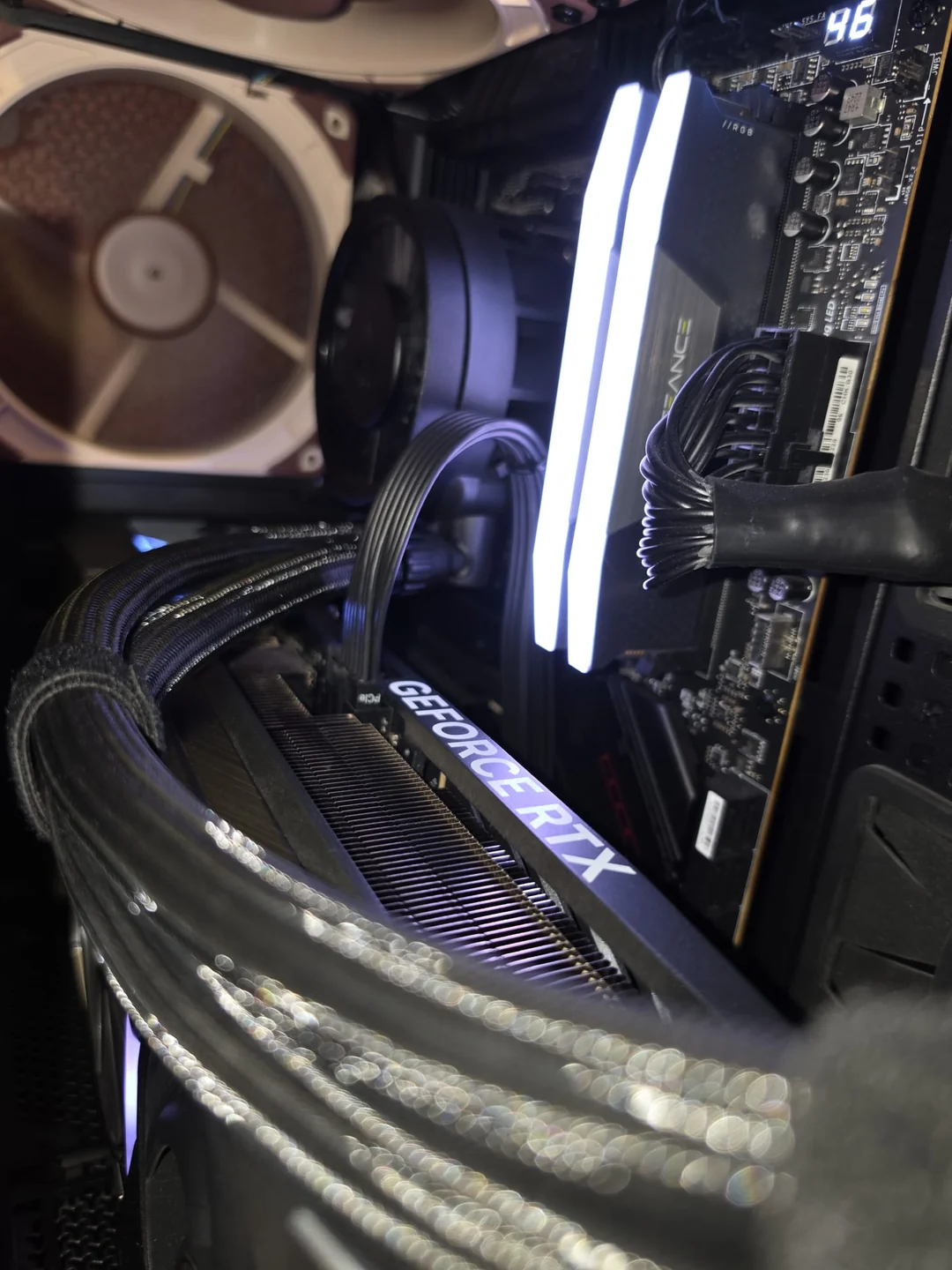 A GeForce RTX graphics card installed inside a PC case with visible Corsair Vengeance RGB RAM modules and a Noctua case fan.