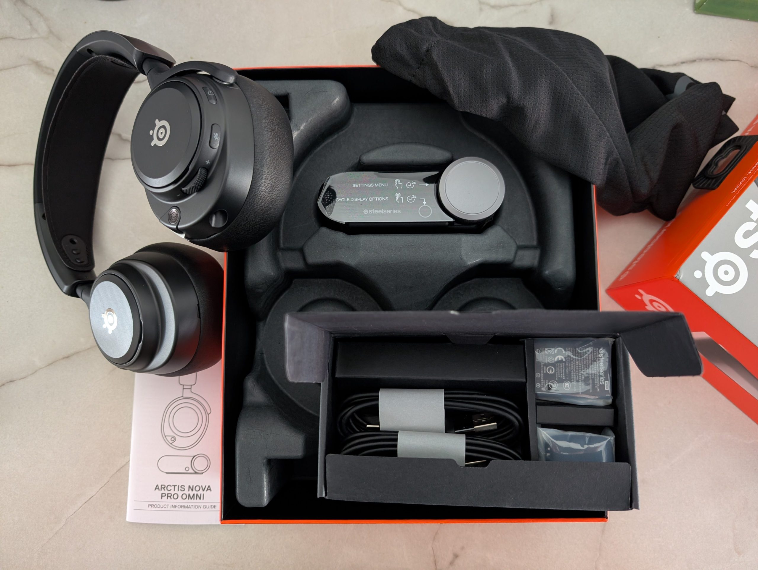 The SteelSeries Arctis Nova Pro Wireless box is open, displaying the headset, charging base, and a 'Quick Setup Guide'.