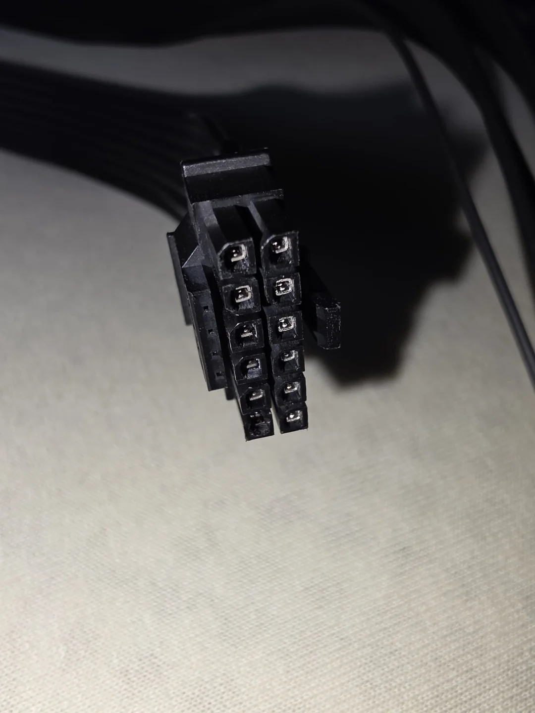 A close-up of a black unbranded 12-pin GPU power connector cable.