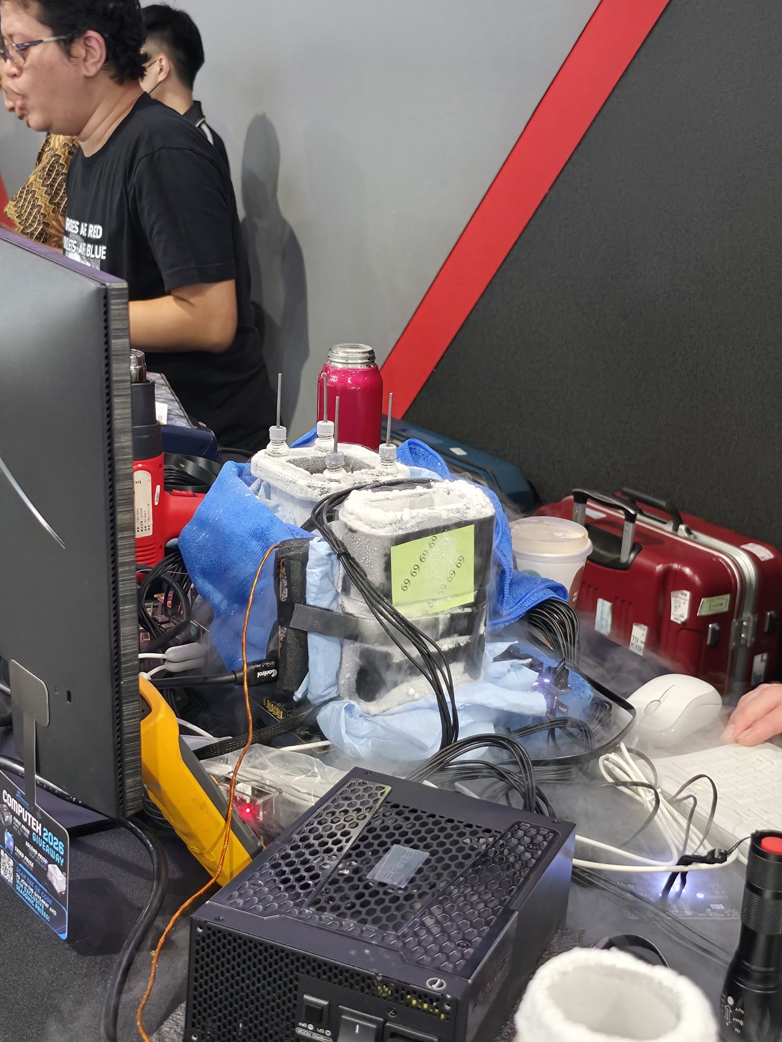 A high-performance computer setup at Computex 2023 is being cooled with liquid nitrogen, visible with frost-covered containers and cables near a 'COMPUTEX 2023' badge.
