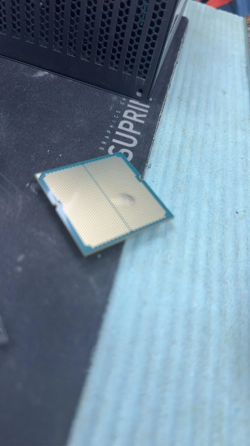 An unbranded CPU lies on a surface with part of the text 'SUPRIM' visible on a mouse pad.