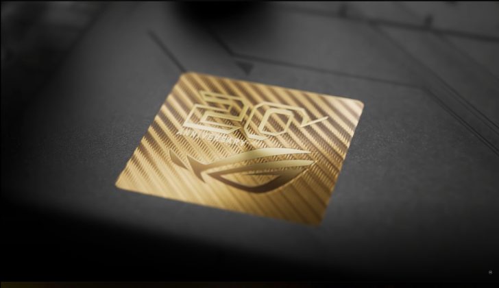 A close-up of a golden emblem on a device featuring the ASUS ROG logo and the text '20th Anniversary'.