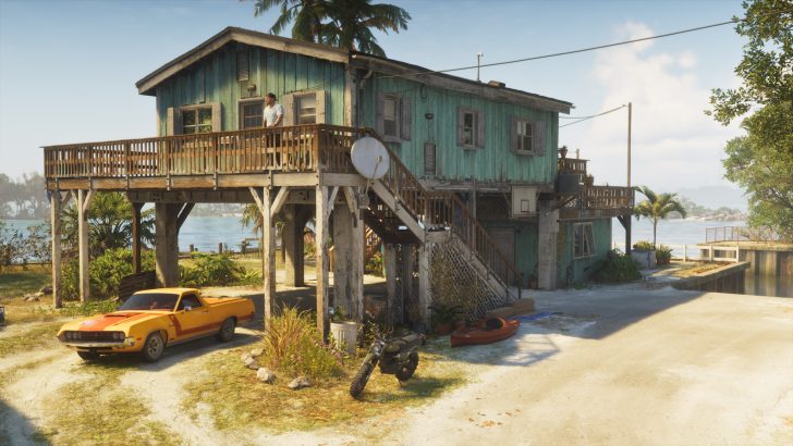 A character in the game 'Call of Duty: Warzone' stands on the balcony of a rustic wooden house beside a yellow car and a motorcycle.