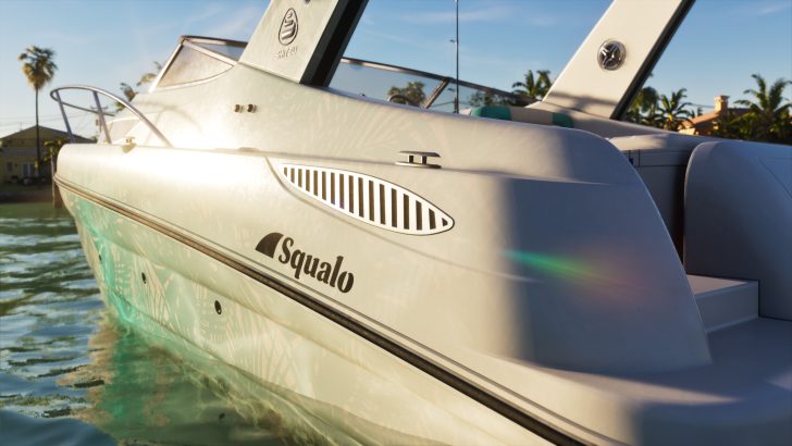 A close-up of a Shitzu Squalo boat docked near a palm-lined shore under a clear sky.