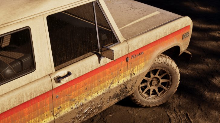 A close-up view of a mud-splattered, vintage SUV with the word 'Riviera' on its side and a red-orange stripe, showing dirt accumulation on the vehicle and tire.