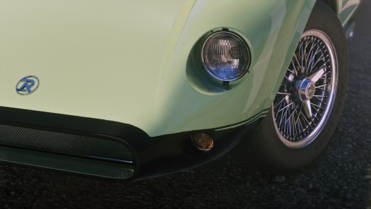 Close-up of a green vintage car front end showing a circular headlamp, chrome wire-spoke wheel, and a blue 'R' logo on the bumper.